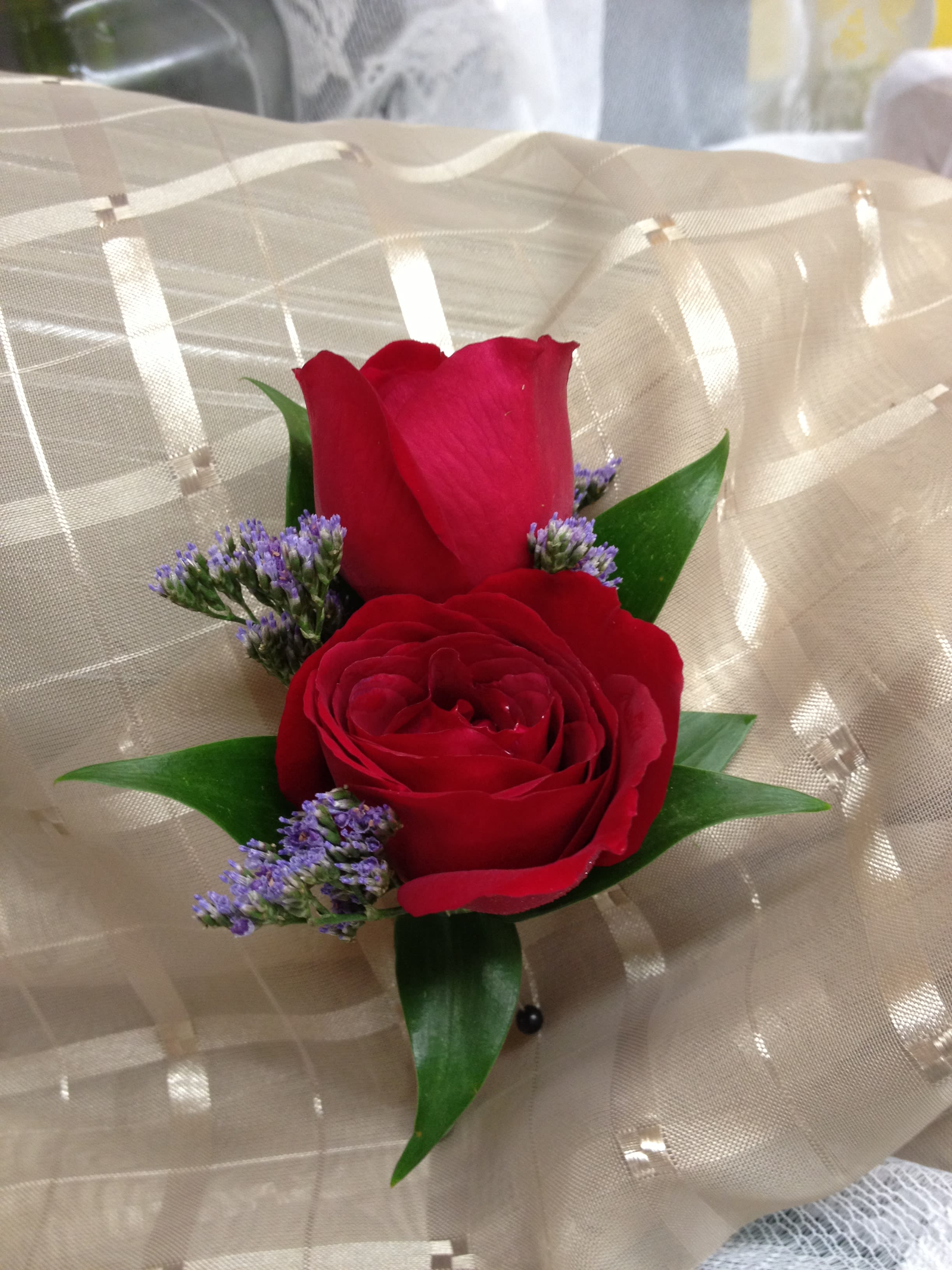 Two red roses with purple filler wrapped in beige mesh