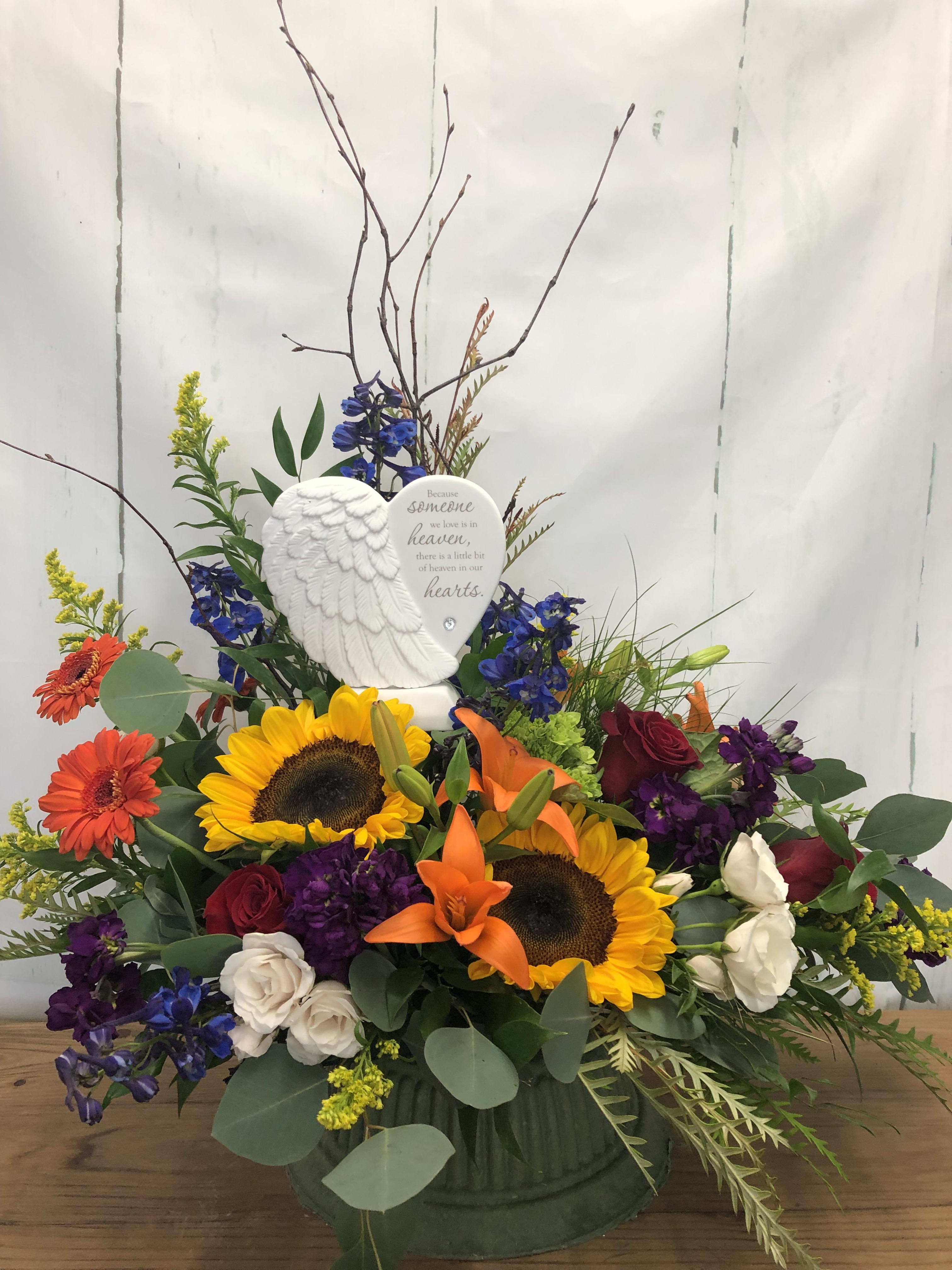 Sympathy arrangement with sunflowers, roses, and an angel plaque