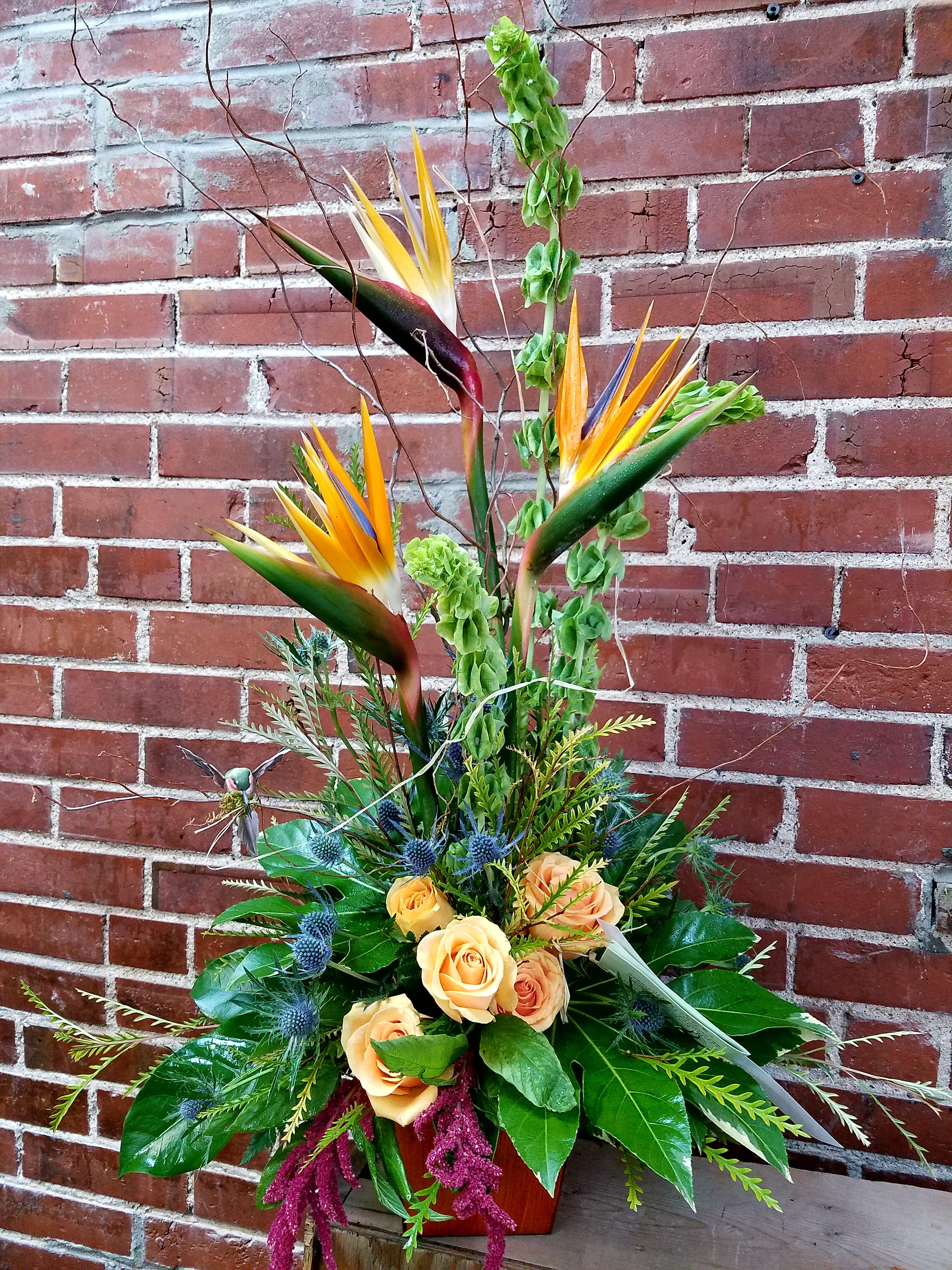 Tropical flower arrangement with orange roses and bird-of-paradise blooms