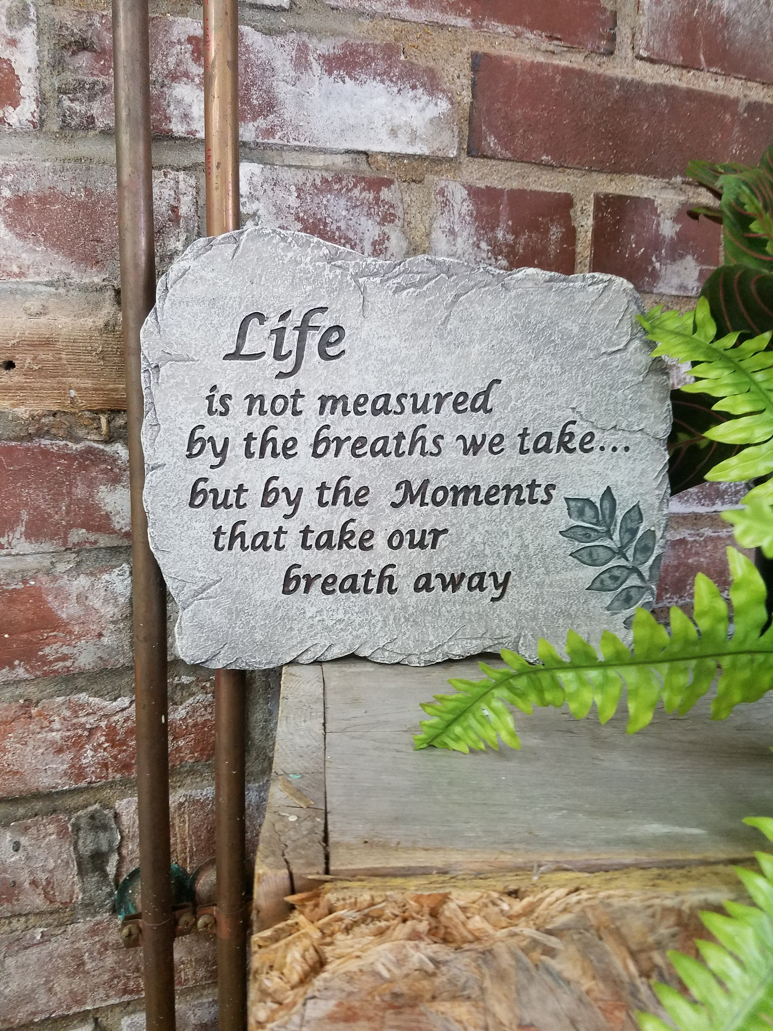 Stone plaque with a quote against a brick wall