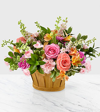 Mixed bouquet of pink and peach flowers in a wooden basket