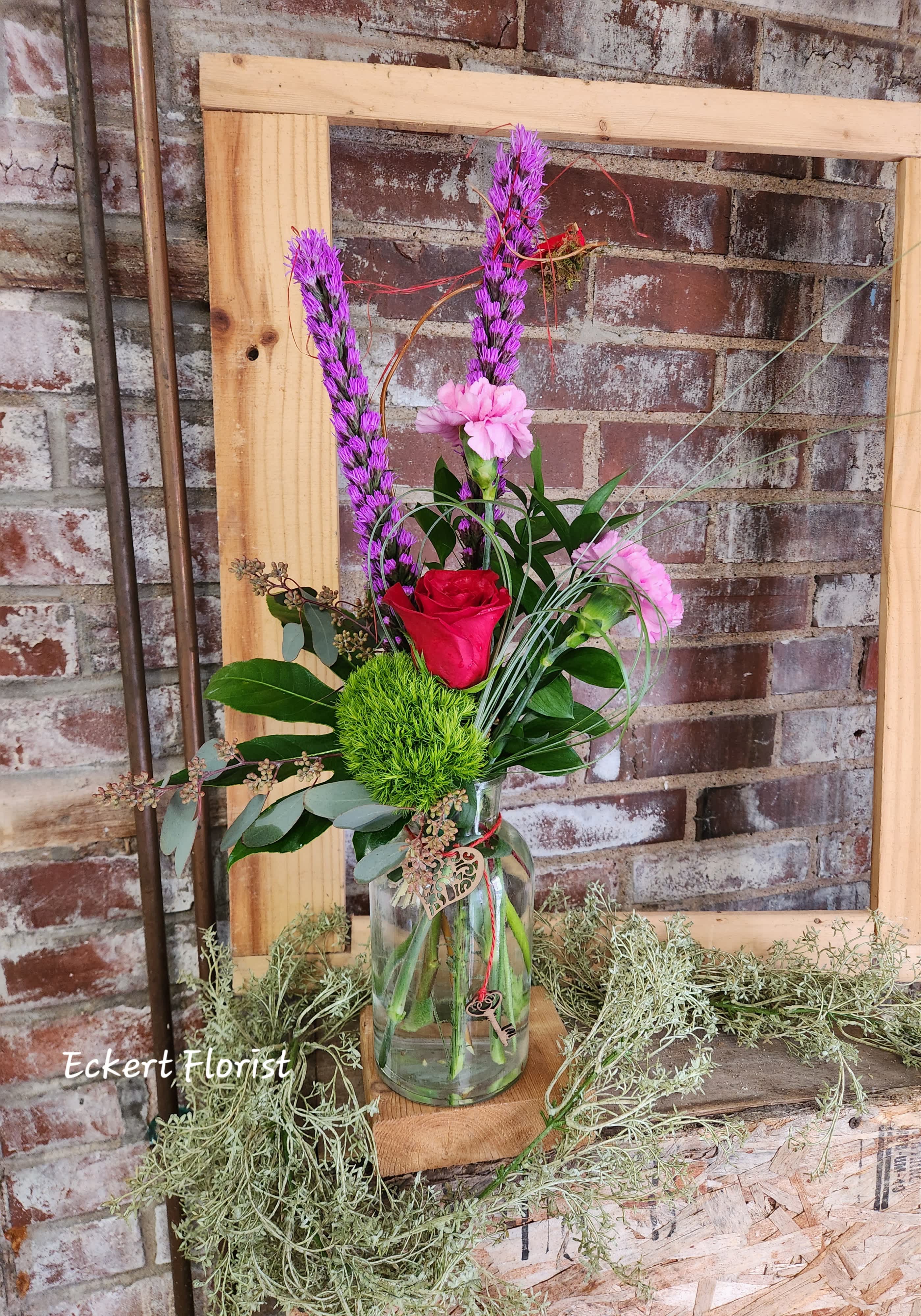 Mixed floral arrangement in a glass vase with pink and red blooms