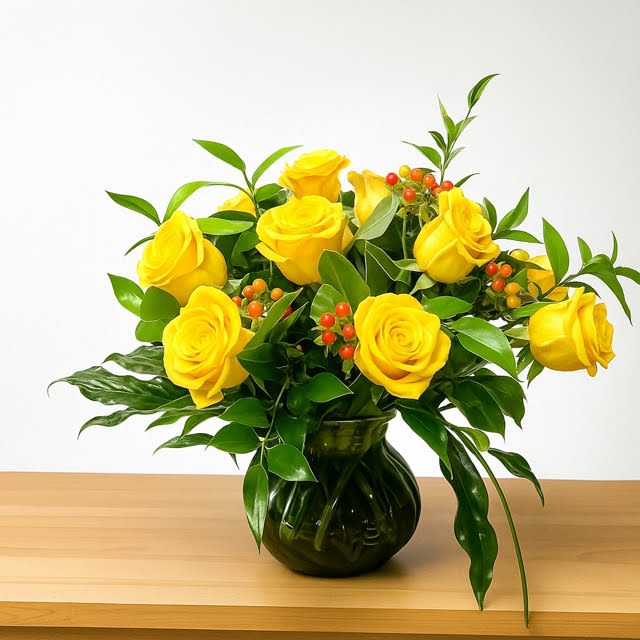 Yellow roses arranged in a dark glass vase with green foliage