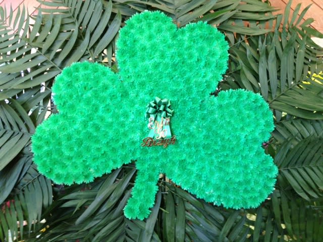 Green shamrock-shaped floral display with a ribbon centerpiece