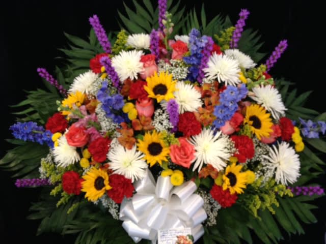 Large mixed bouquet with sunflowers, white blooms, and a white ribbon bow