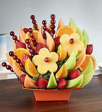 Fruit arrangement with orange slices, strawberries, melon, and grapes in an orange container
