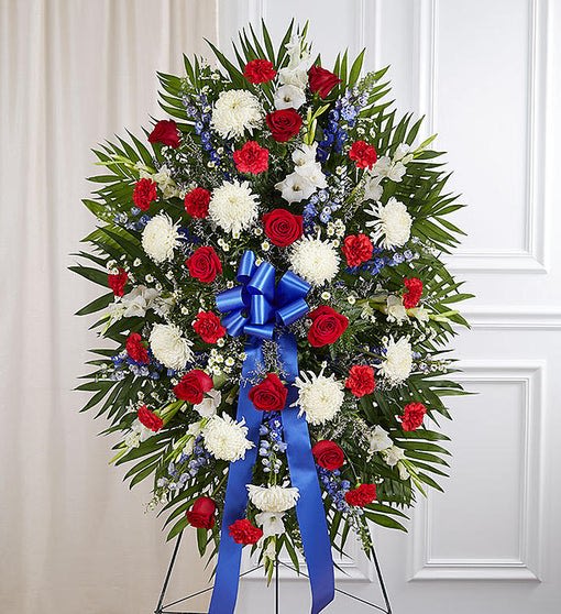 Standing floral wreath with red and white flowers and a blue ribbon