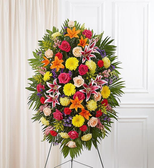 Large standing floral spray with mixed bright flowers on an easel