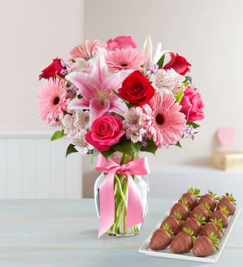 Pink and red mixed bouquet in a glass vase with a pink ribbon