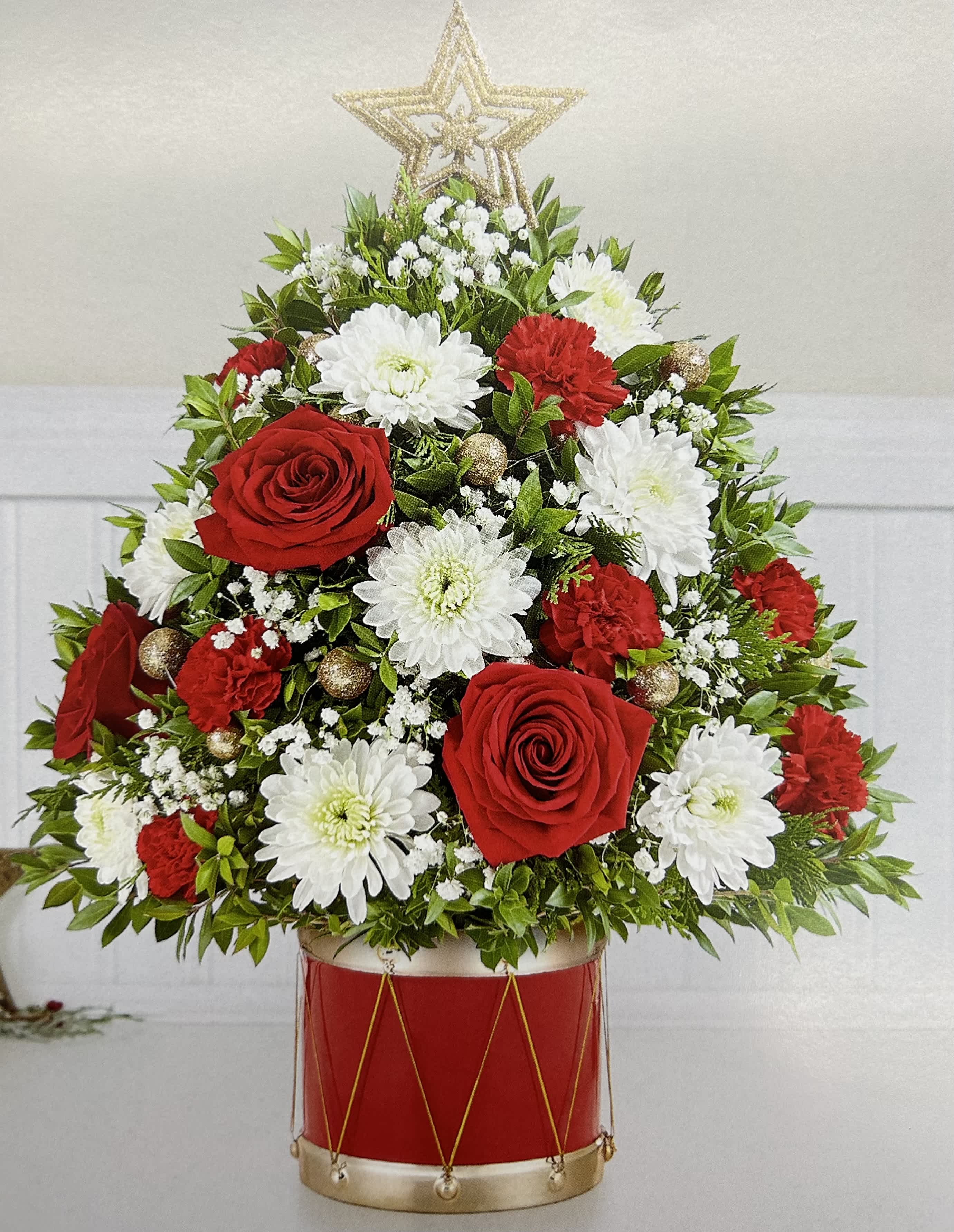 Red roses and white chrysanthemums arranged in a red drum container with a star topper
