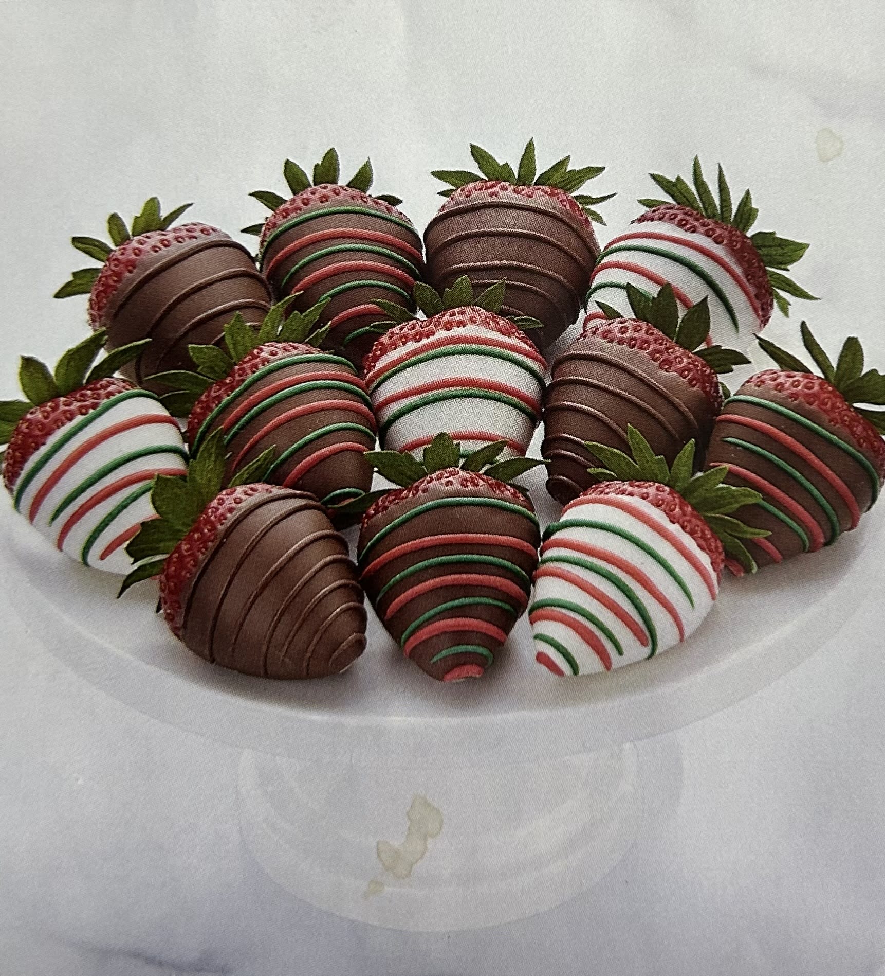 Plate of chocolate-covered strawberries with red, green, and white drizzle