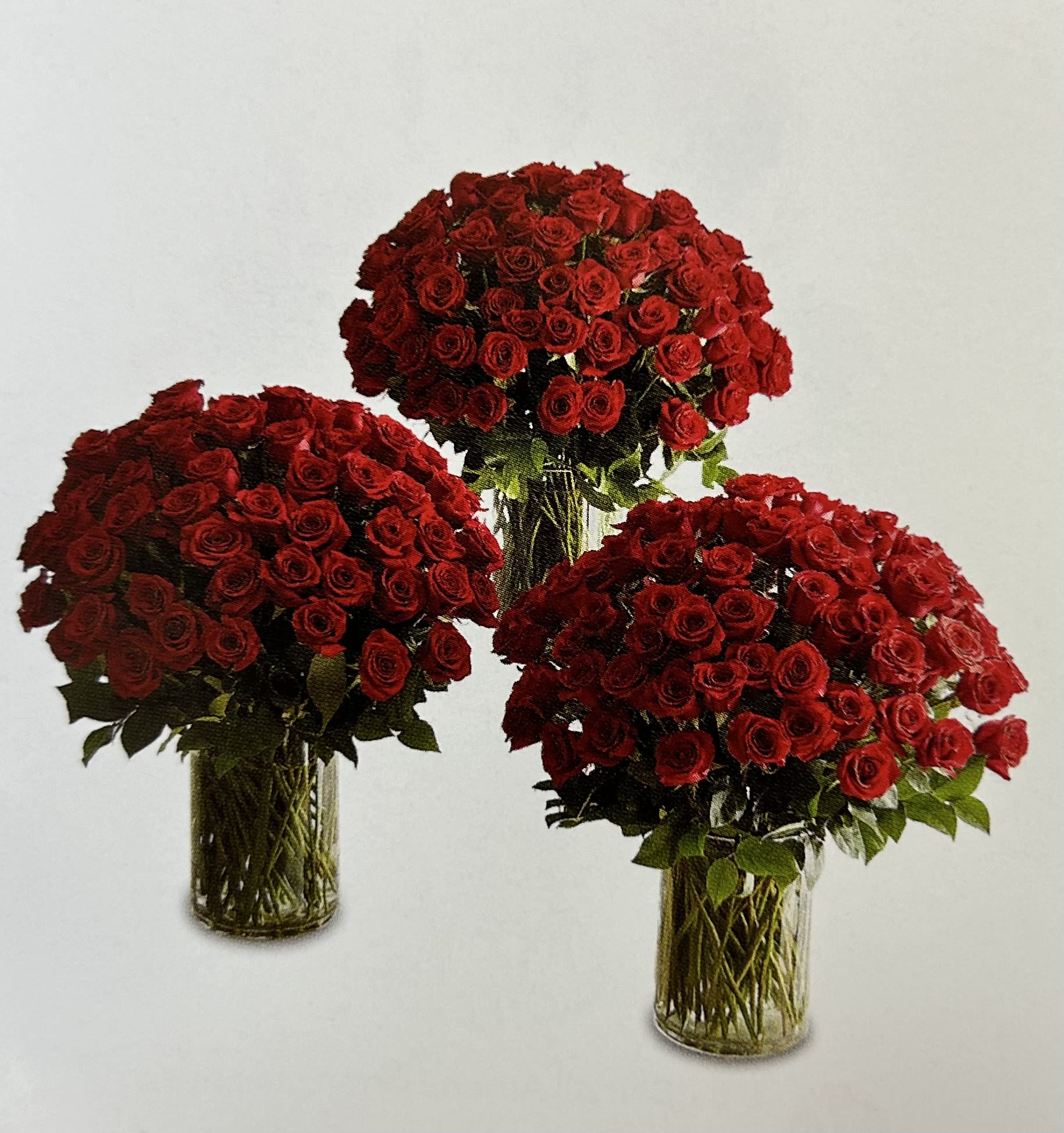 Three red rose arrangements in clear glass vases
