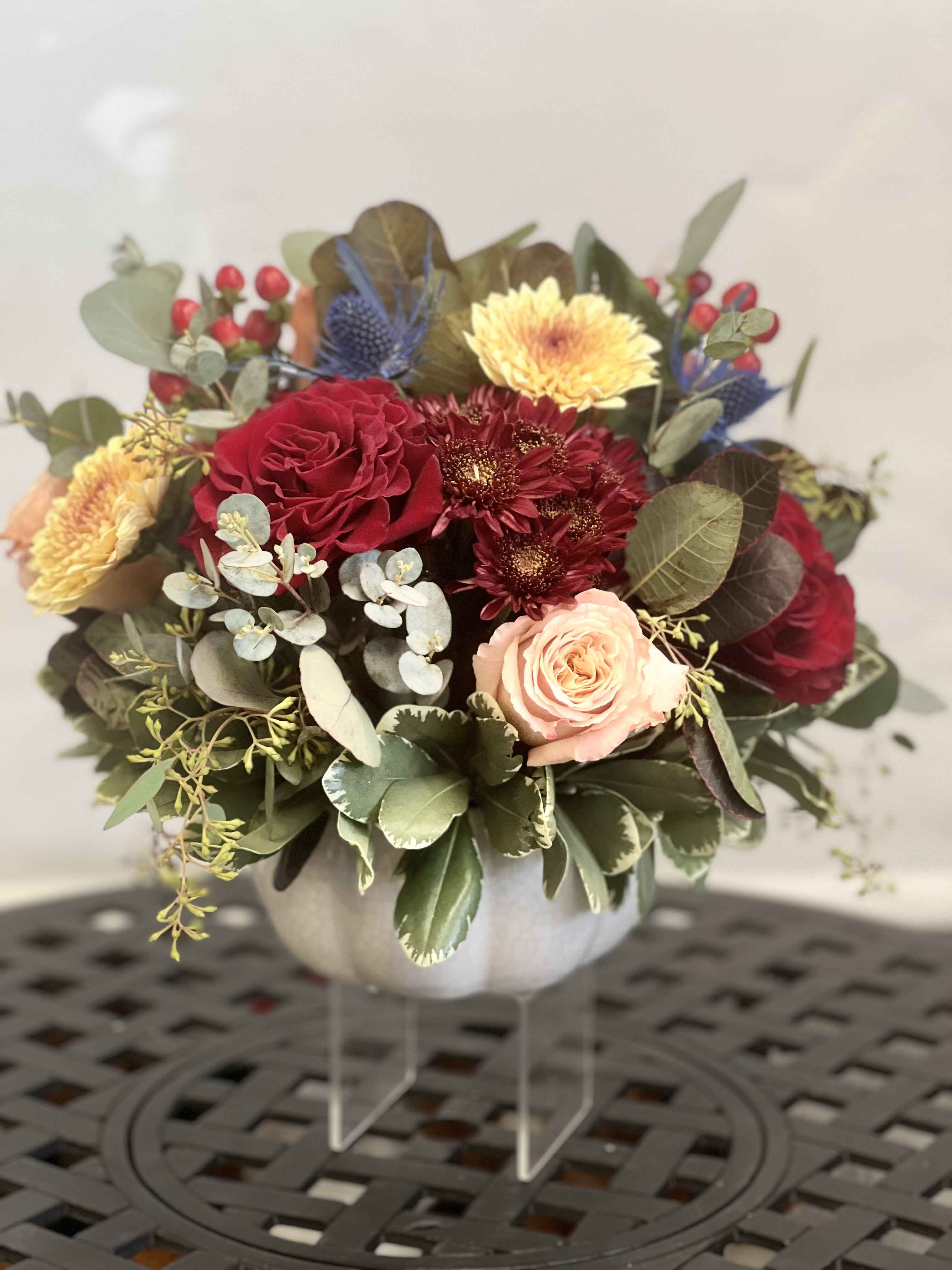 Mixed bouquet in a white vase with red, peach, and yellow blooms