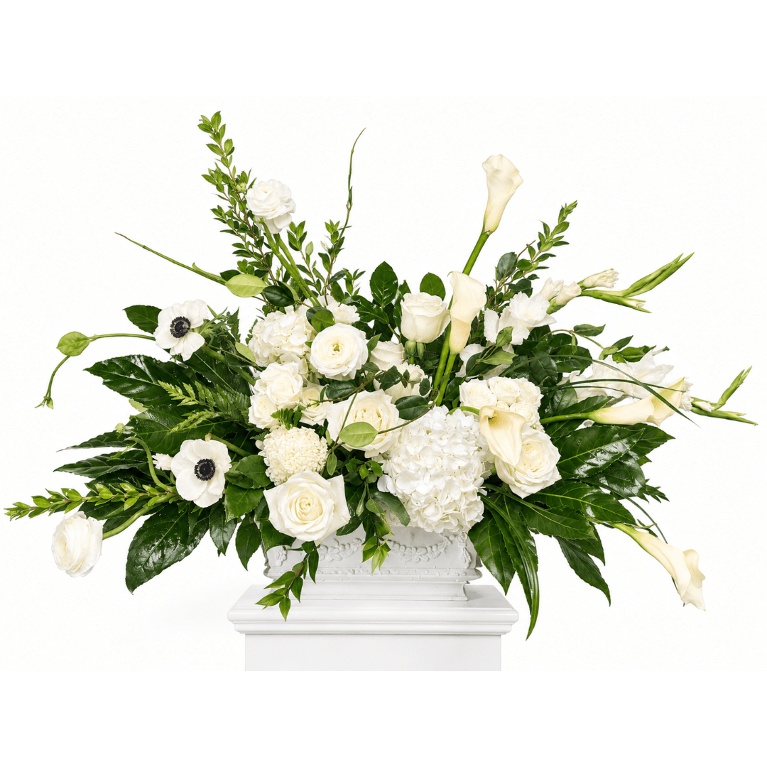 White floral arrangement with roses, calla lilies, and hydrangeas in a white vase