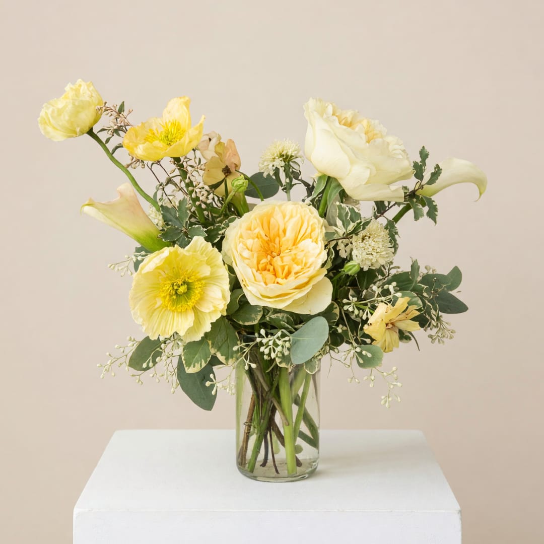 Yellow and cream flower arrangement in a clear glass vase