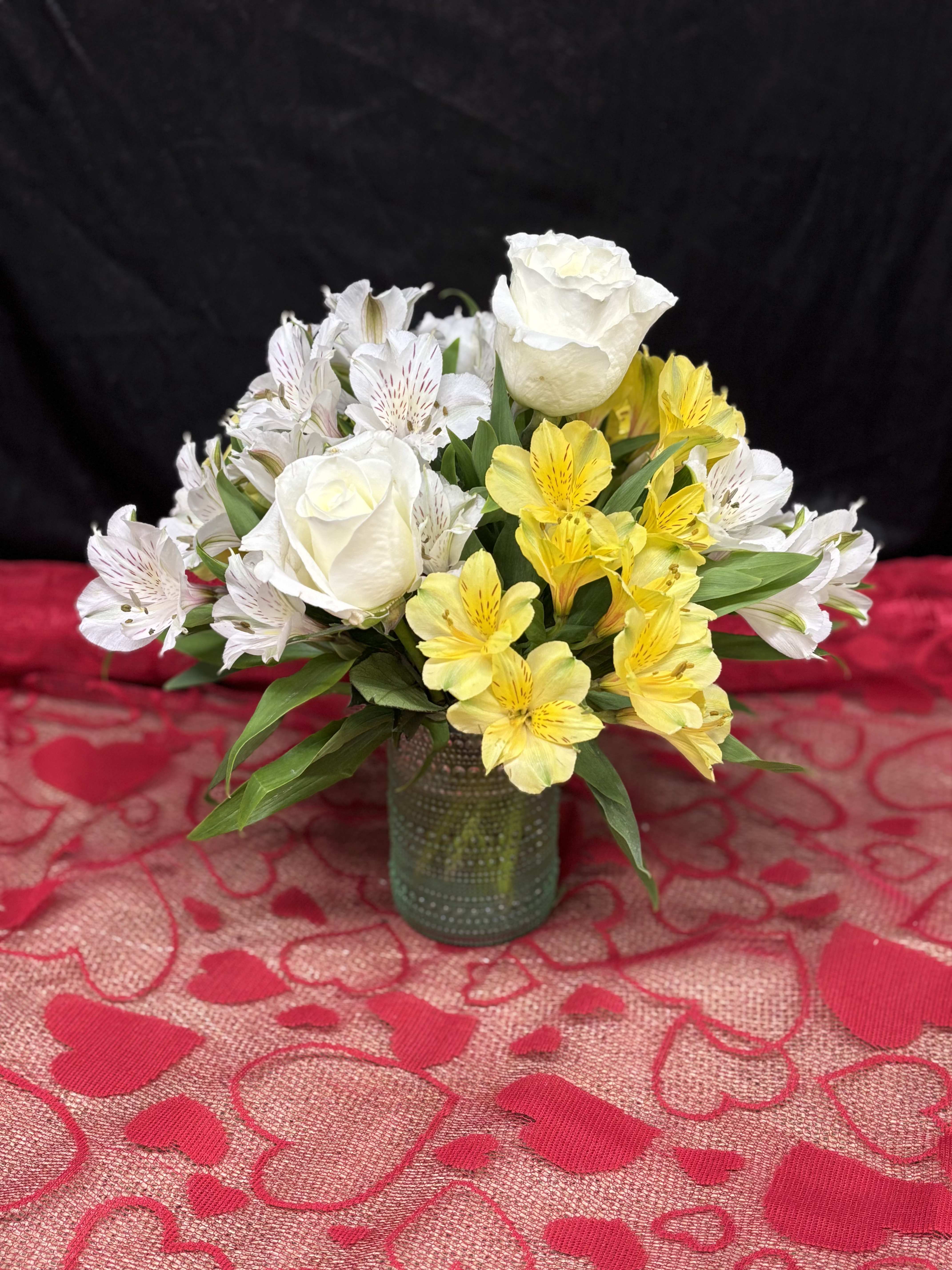 White roses and yellow alstroemeria in a small glass vase