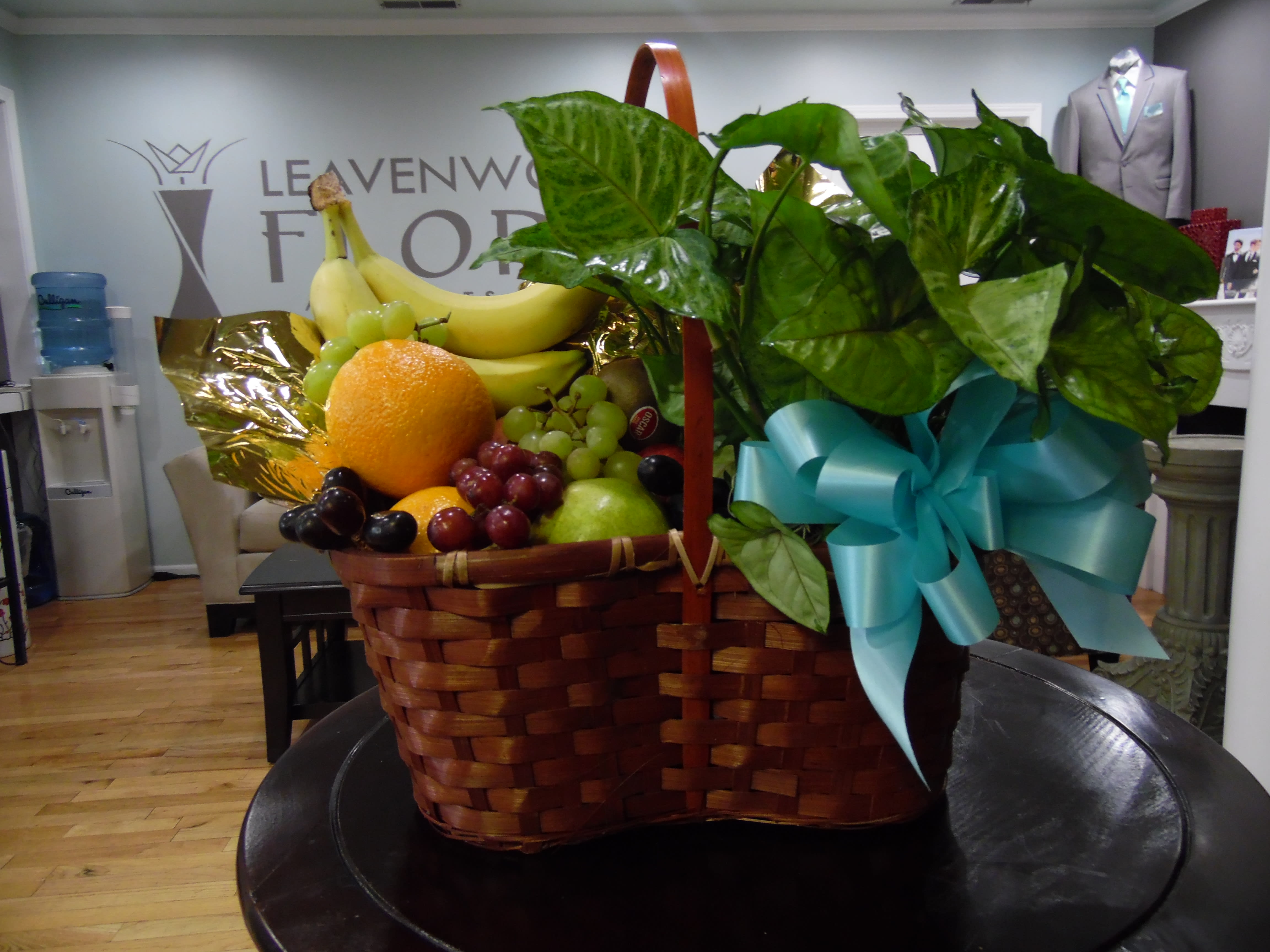 Fruit basket with bananas, grapes, oranges, and a blue ribbon