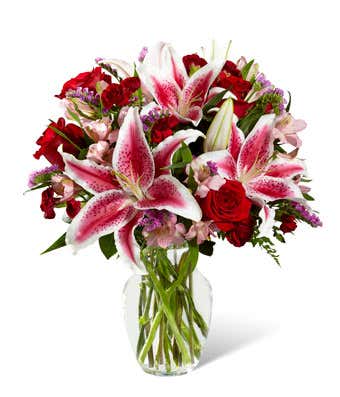 Bouquet of pink lilies and red roses in a clear glass vase