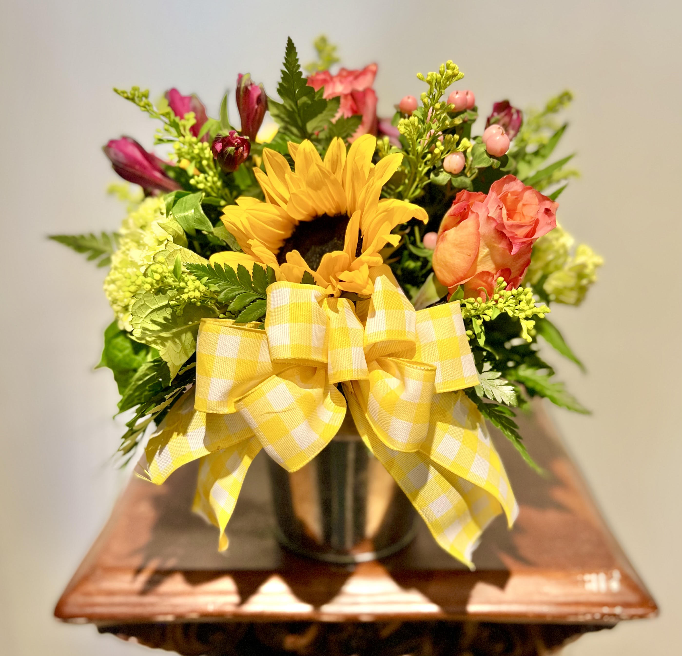 Sunflower bouquet with pink roses in a vase and yellow ribbon