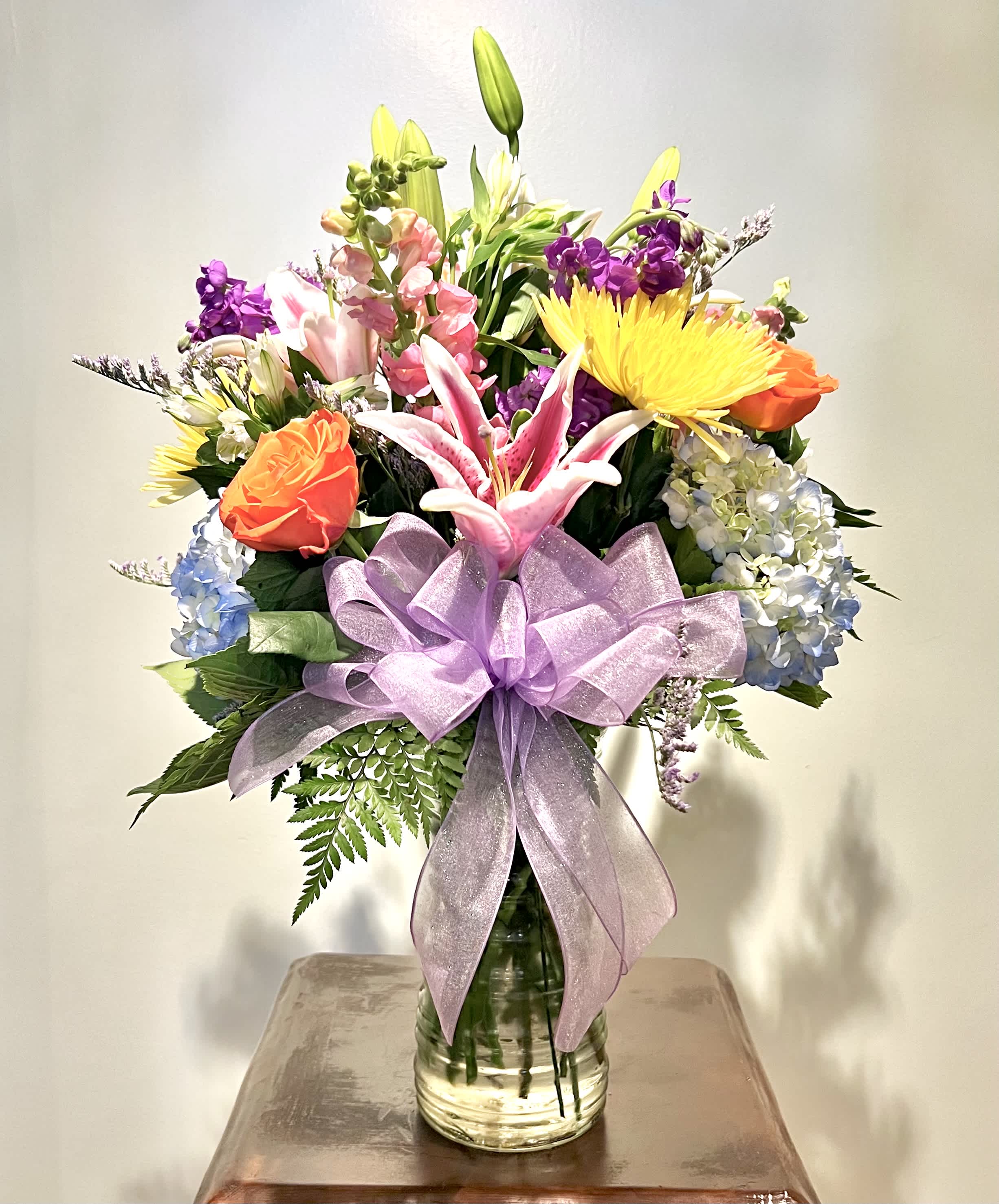 Mixed bouquet in a glass vase with a lavender ribbon