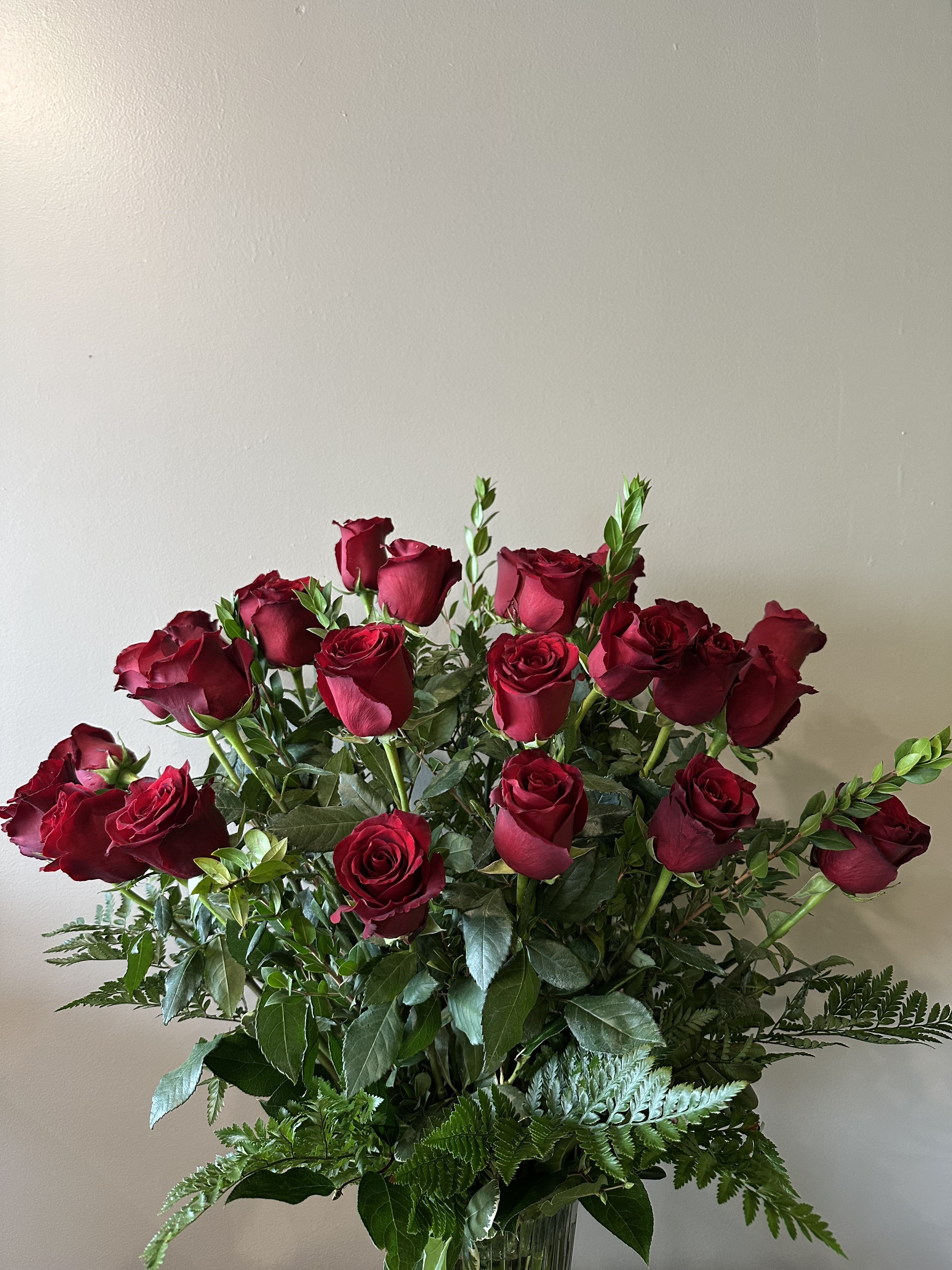 Bouquet of red roses with greenery in a clear vase