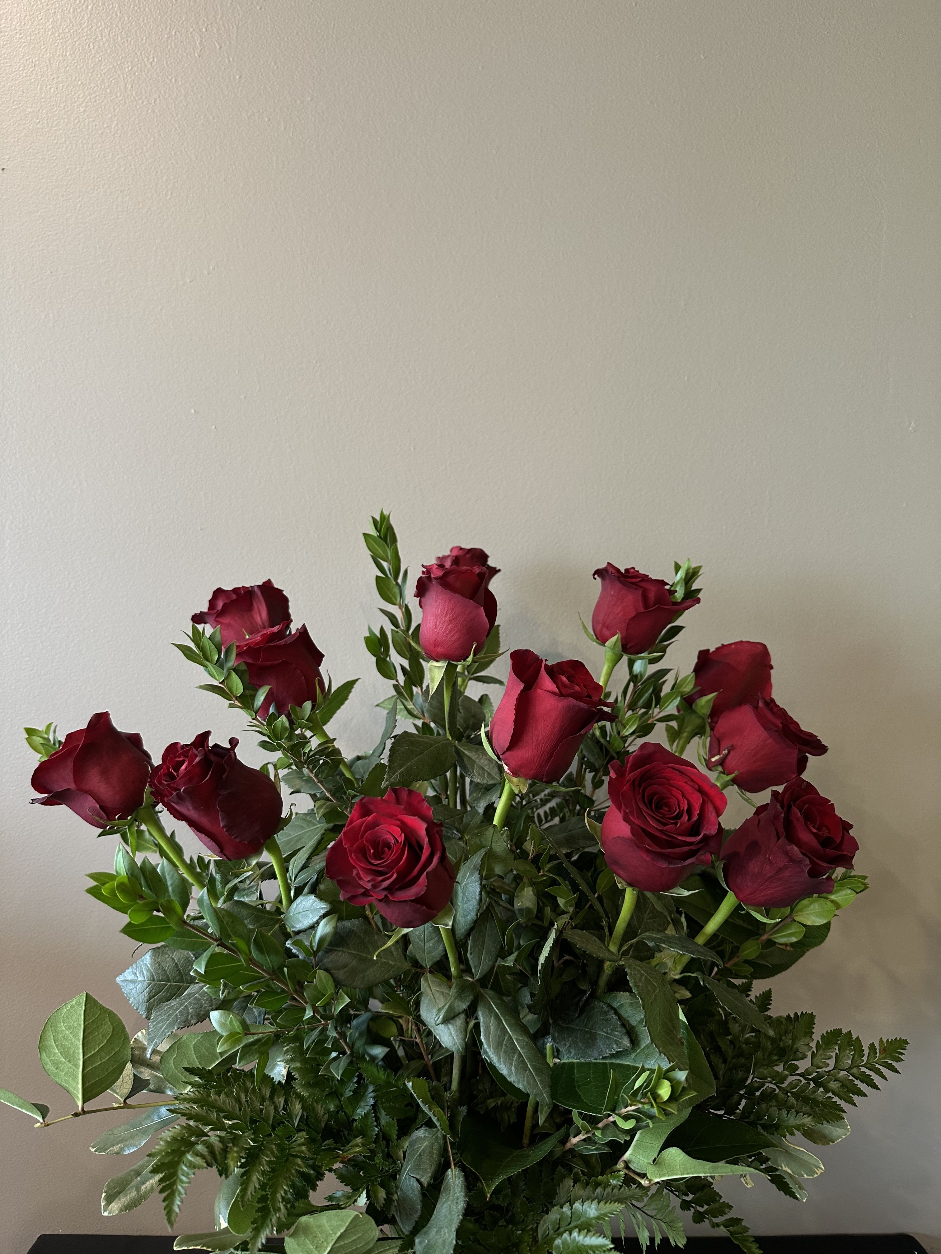 Tall arrangement of long-stemmed red roses with abundant foliage