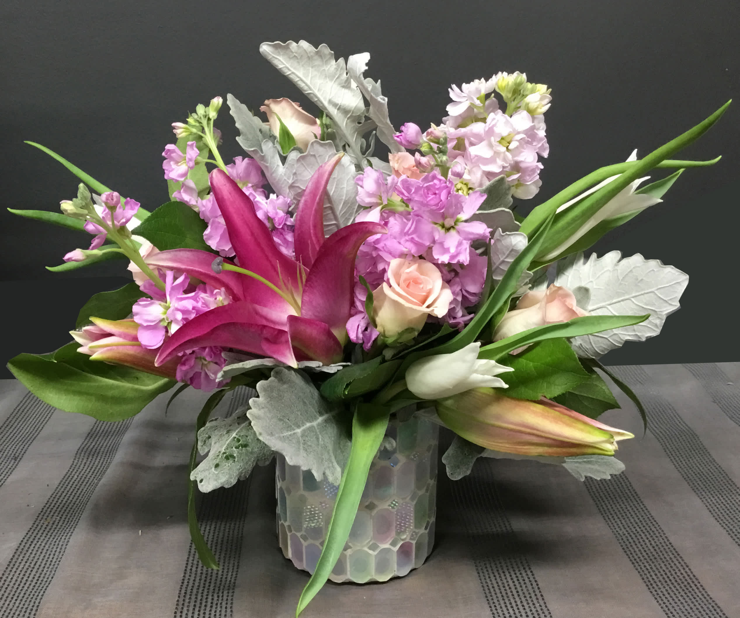 Pink lilies and roses arranged in a glass vase