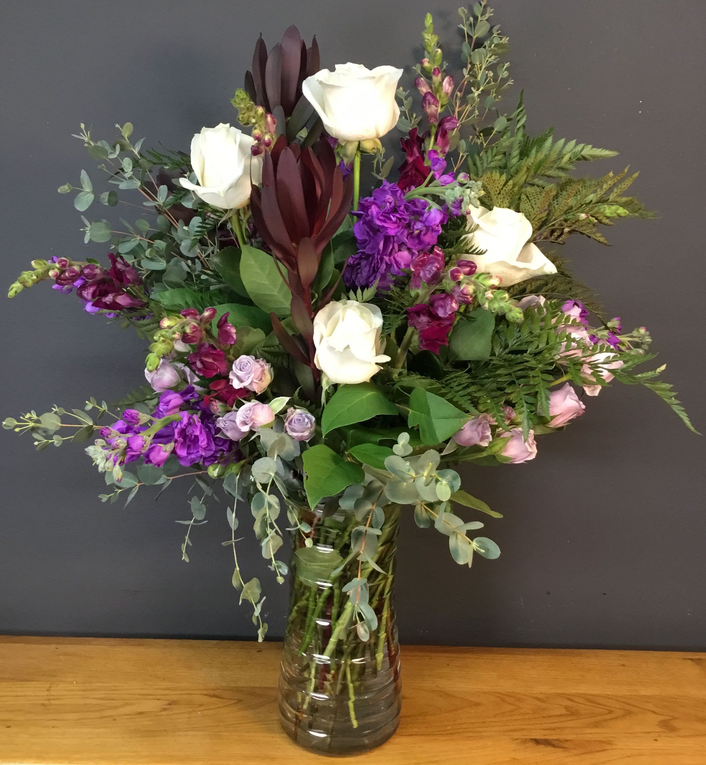 Bouquet of white roses and purple flowers in a glass vase