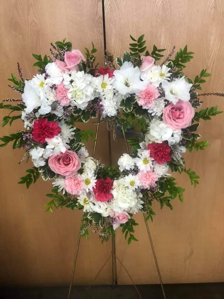 Heart-shaped floral wreath on an easel with pink and white flowers