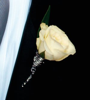 Cream rose boutonniere with a silver accent on a dark suit