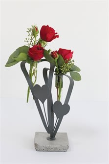 Two small red rose arrangements in a concrete holder