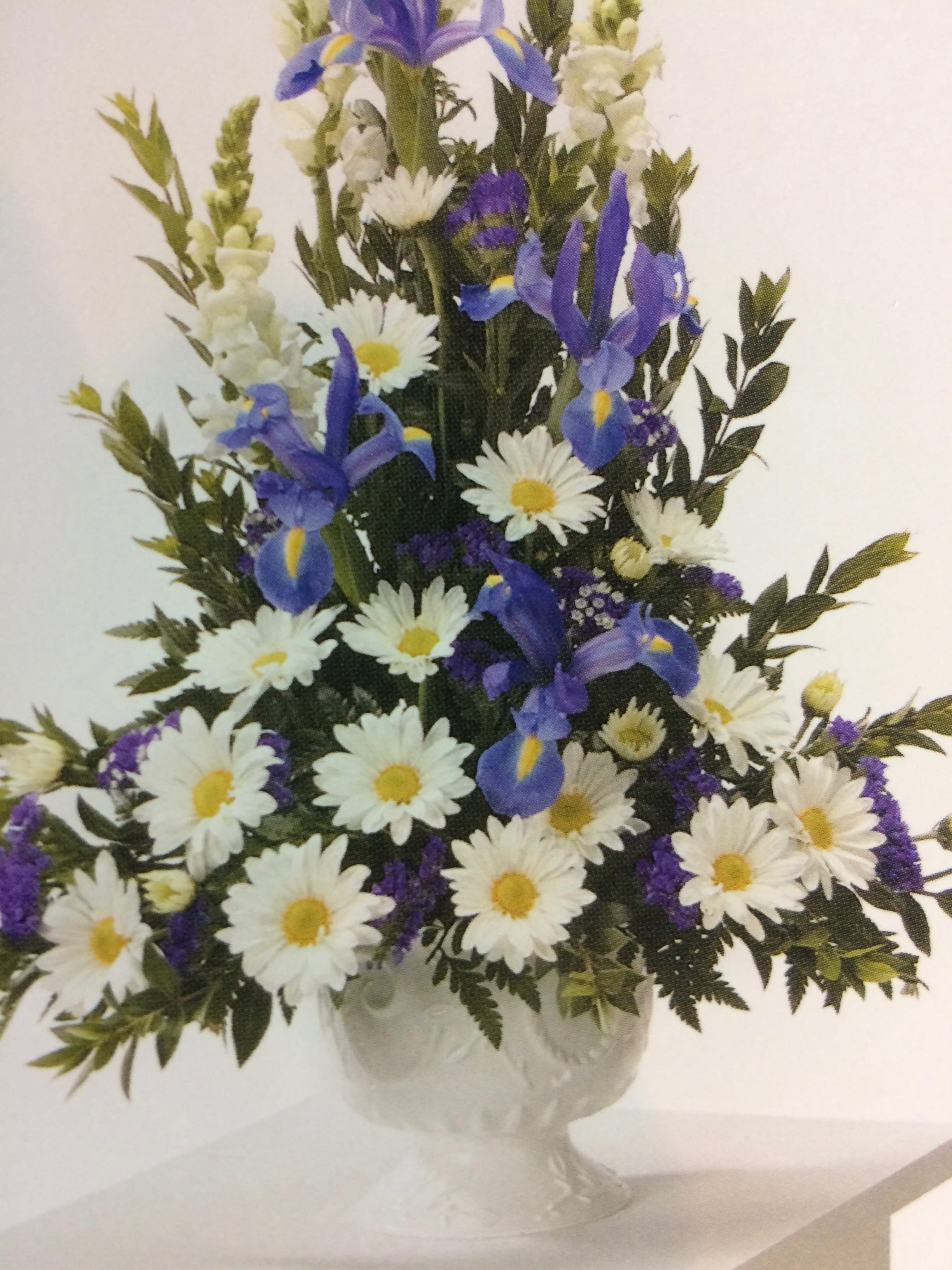 White daisies and blue irises arranged in a clear vase
