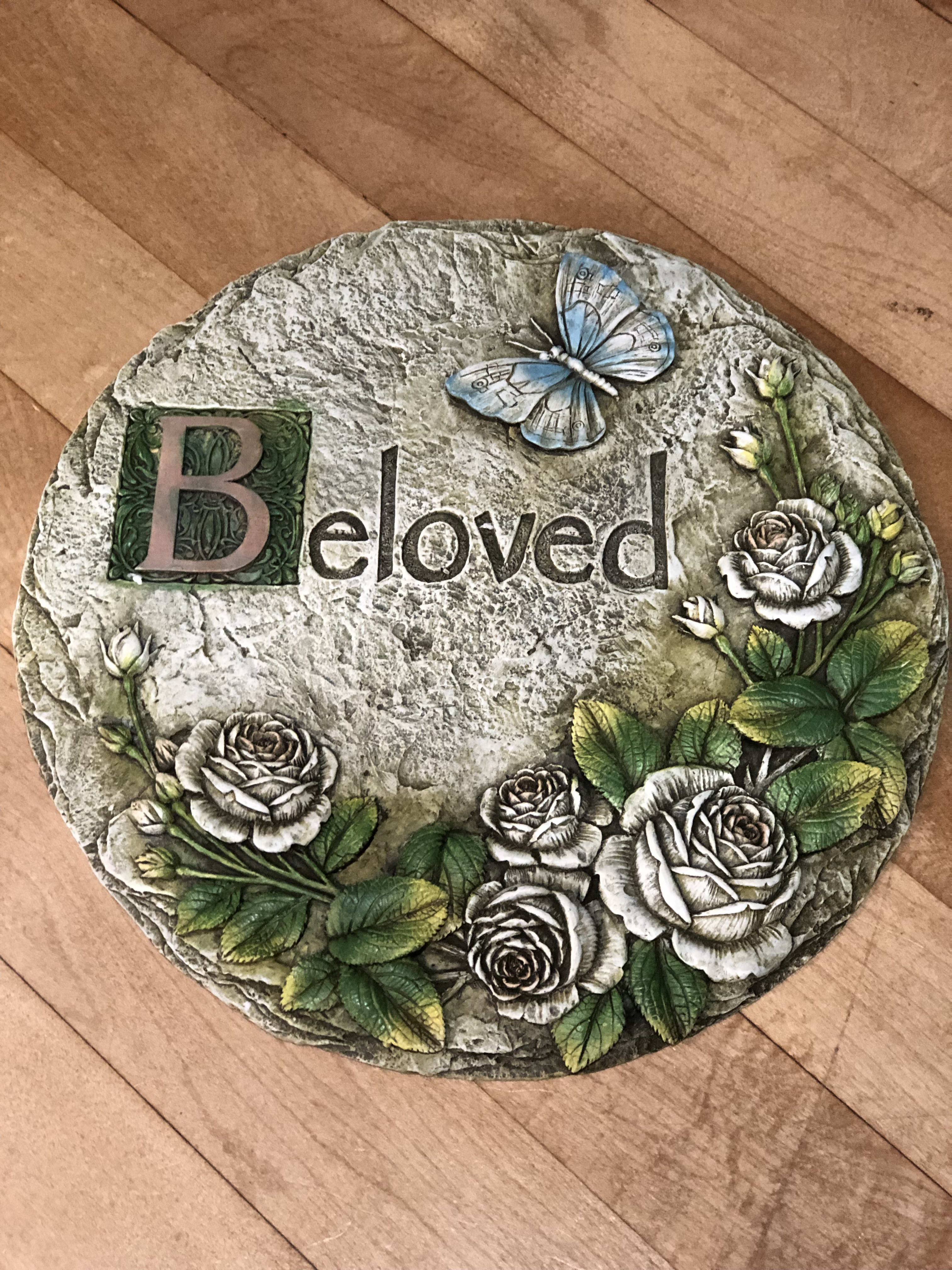 Decorative stone plaque with roses, a butterfly, and the word "Beloved"