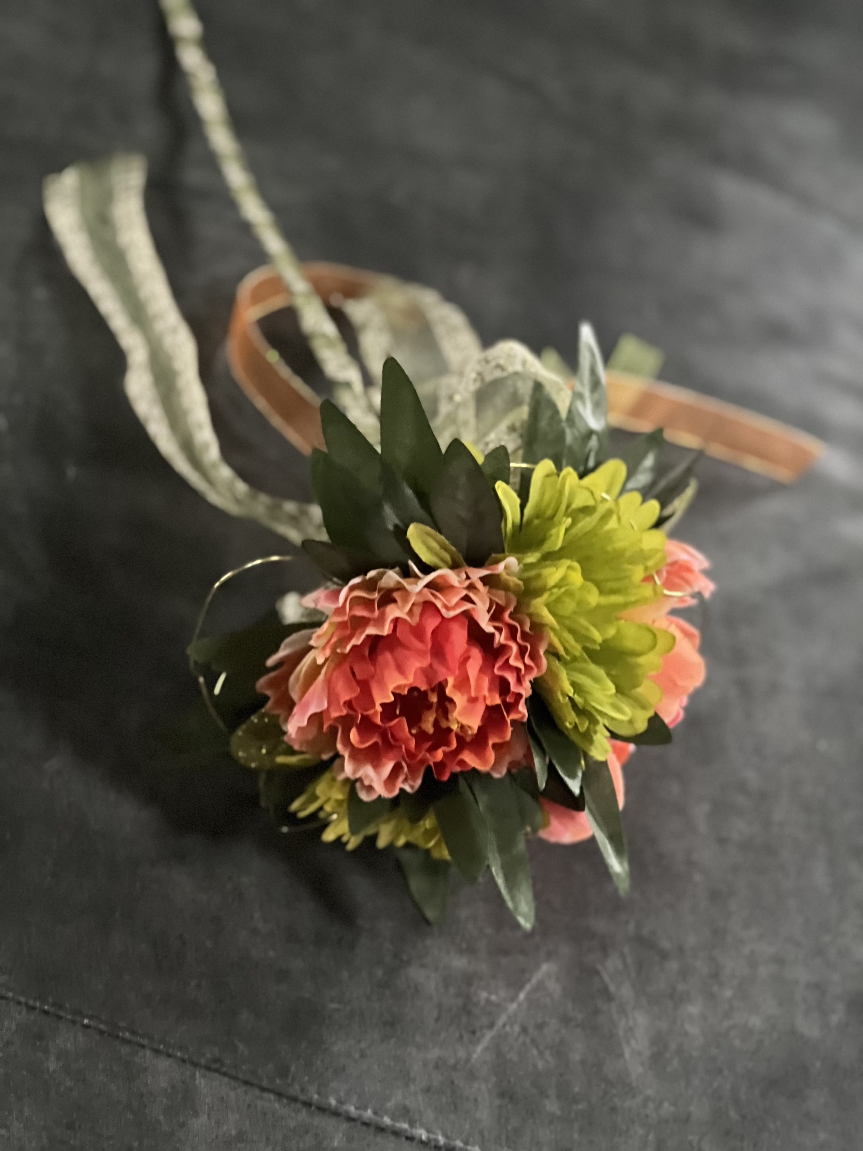 Small floral corsage with pink and yellow blooms on a ribbon band