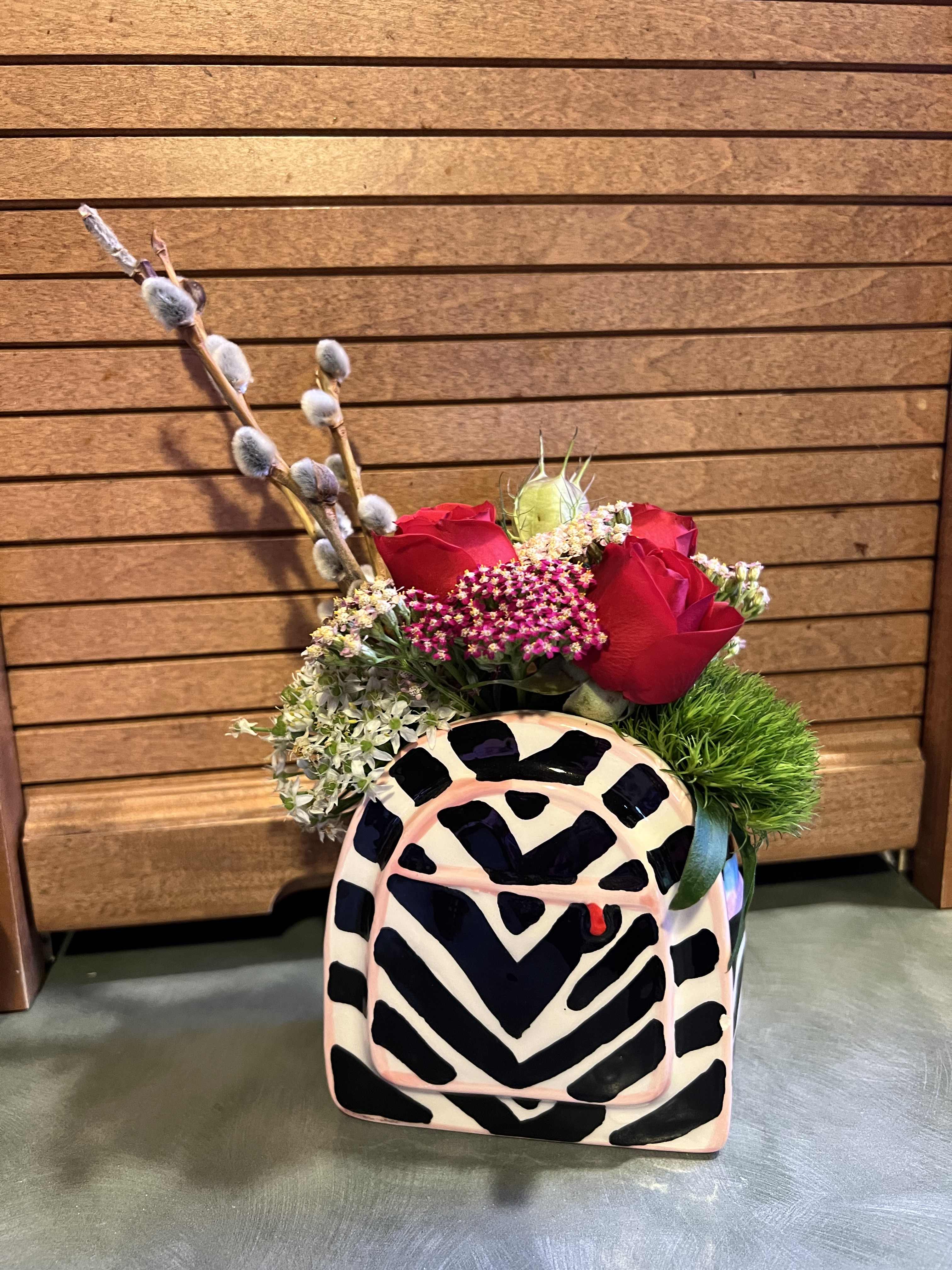 Red roses in a patterned ceramic container with pussy willow branches