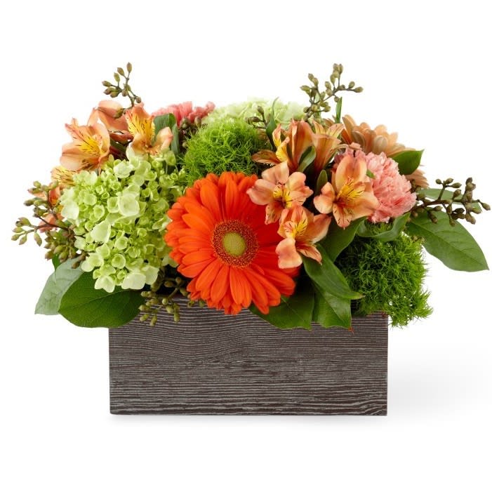 Orange and peach flowers arranged in a wooden box