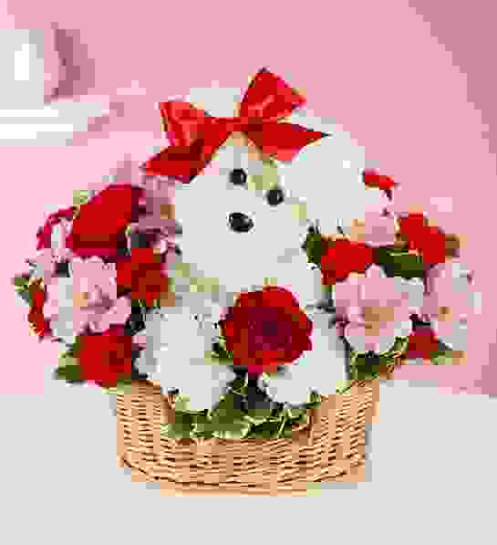 White teddy bear in a basket with red bows and pink flowers