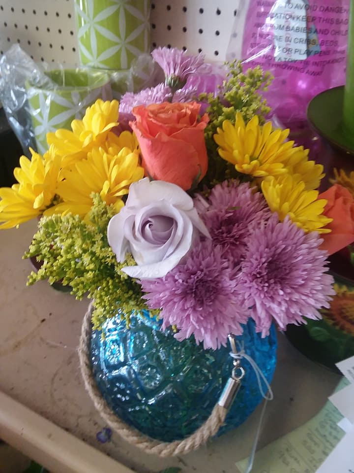 Mixed bouquet with roses and daisies in a blue glass vase