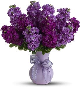 Purple flower bouquet in a lavender vase with a ribbon bow