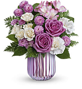 Purple and white flower bouquet in a striped glass vase