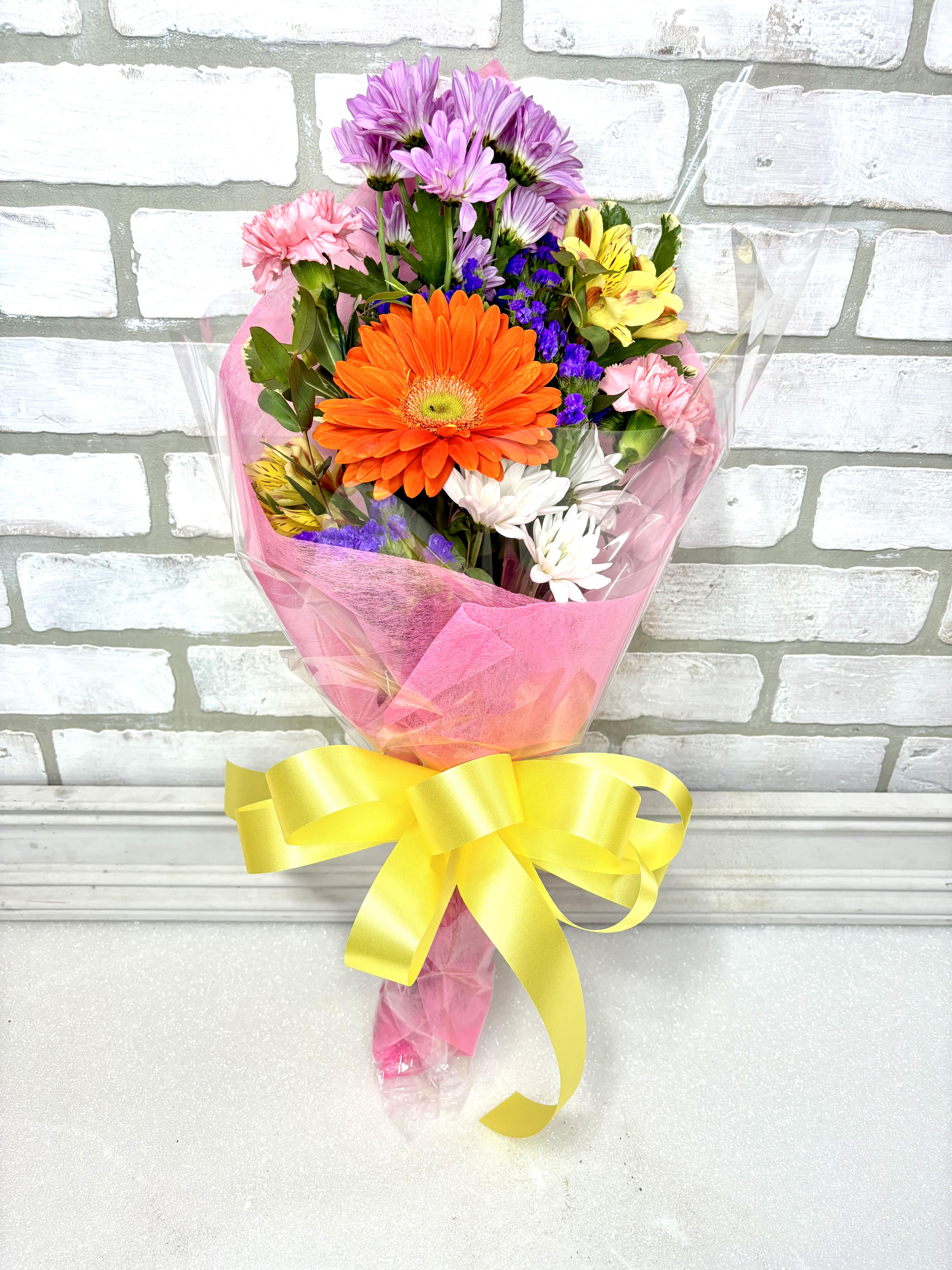 Colorful mixed bouquet with a large orange gerbera daisy and pink ribbon wrap