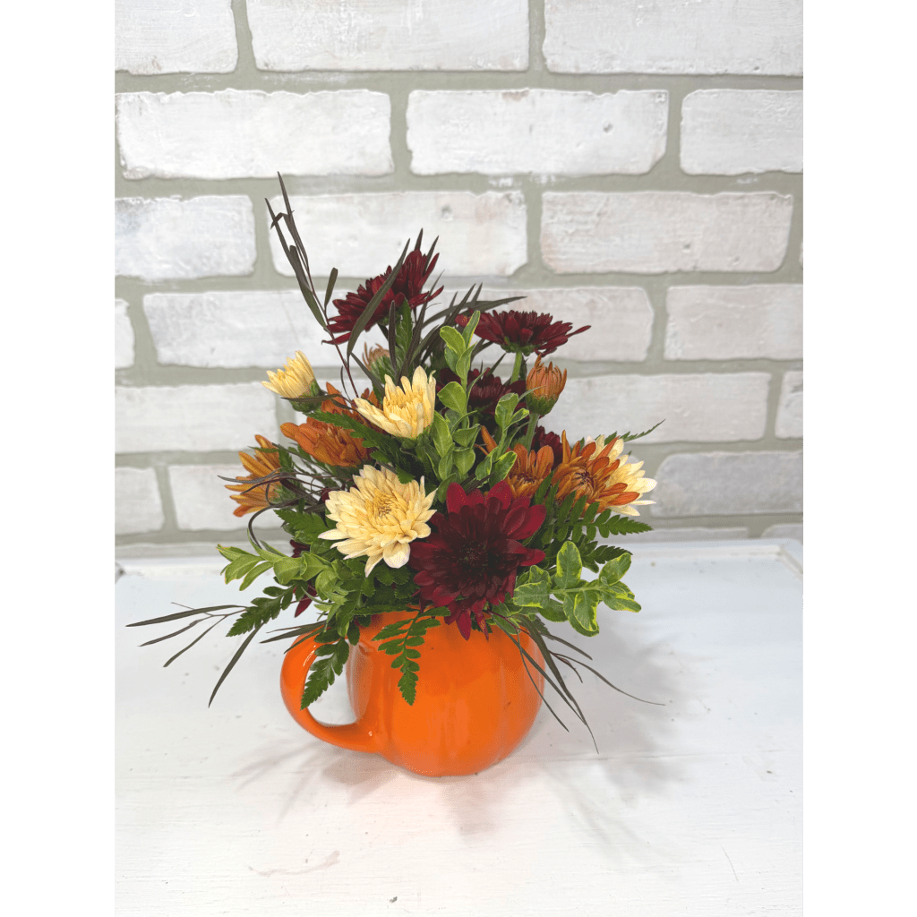 Mixed autumn flowers arranged in an orange mug