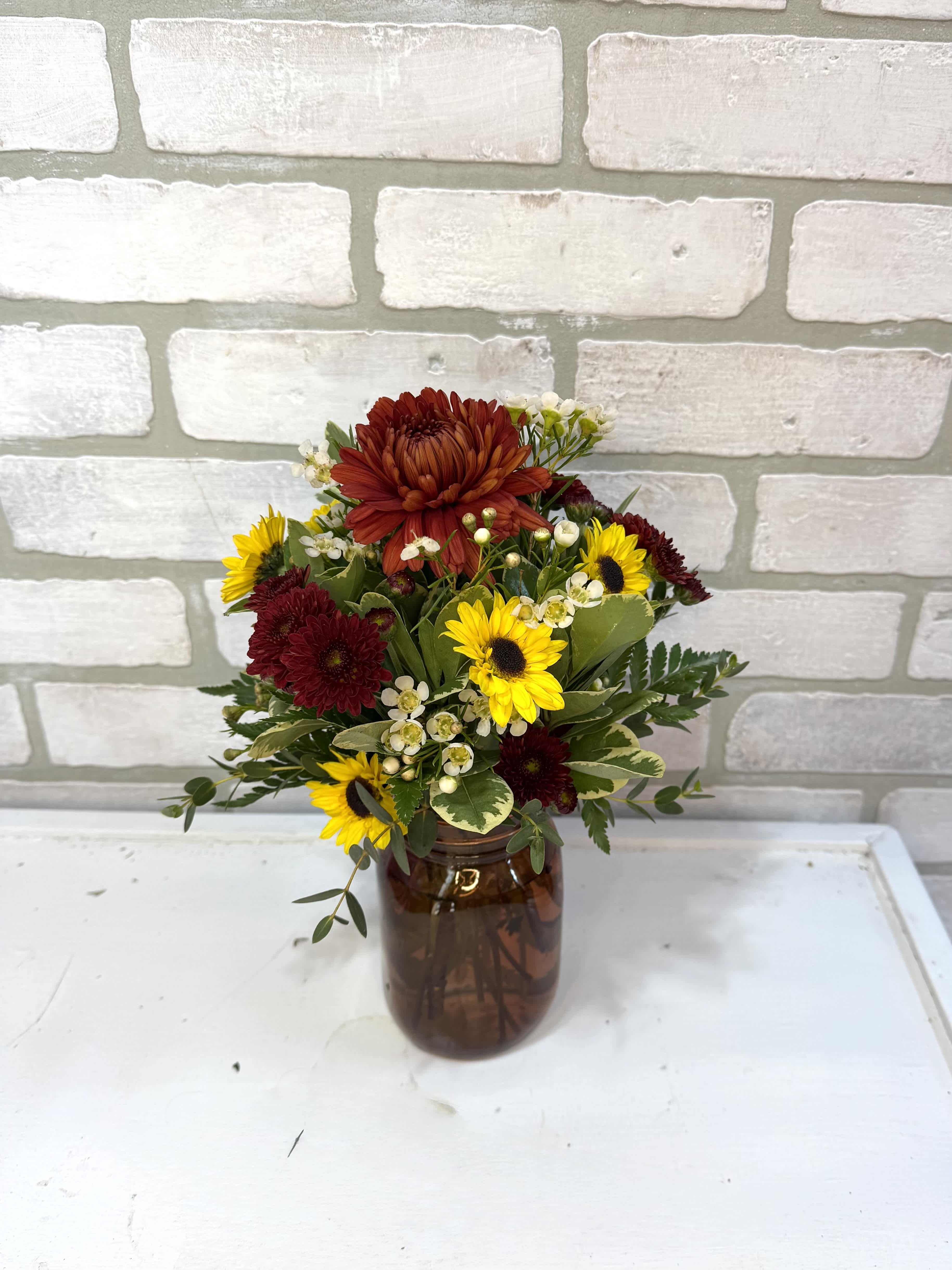 Mixed bouquet of red and yellow flowers in an amber glass vase