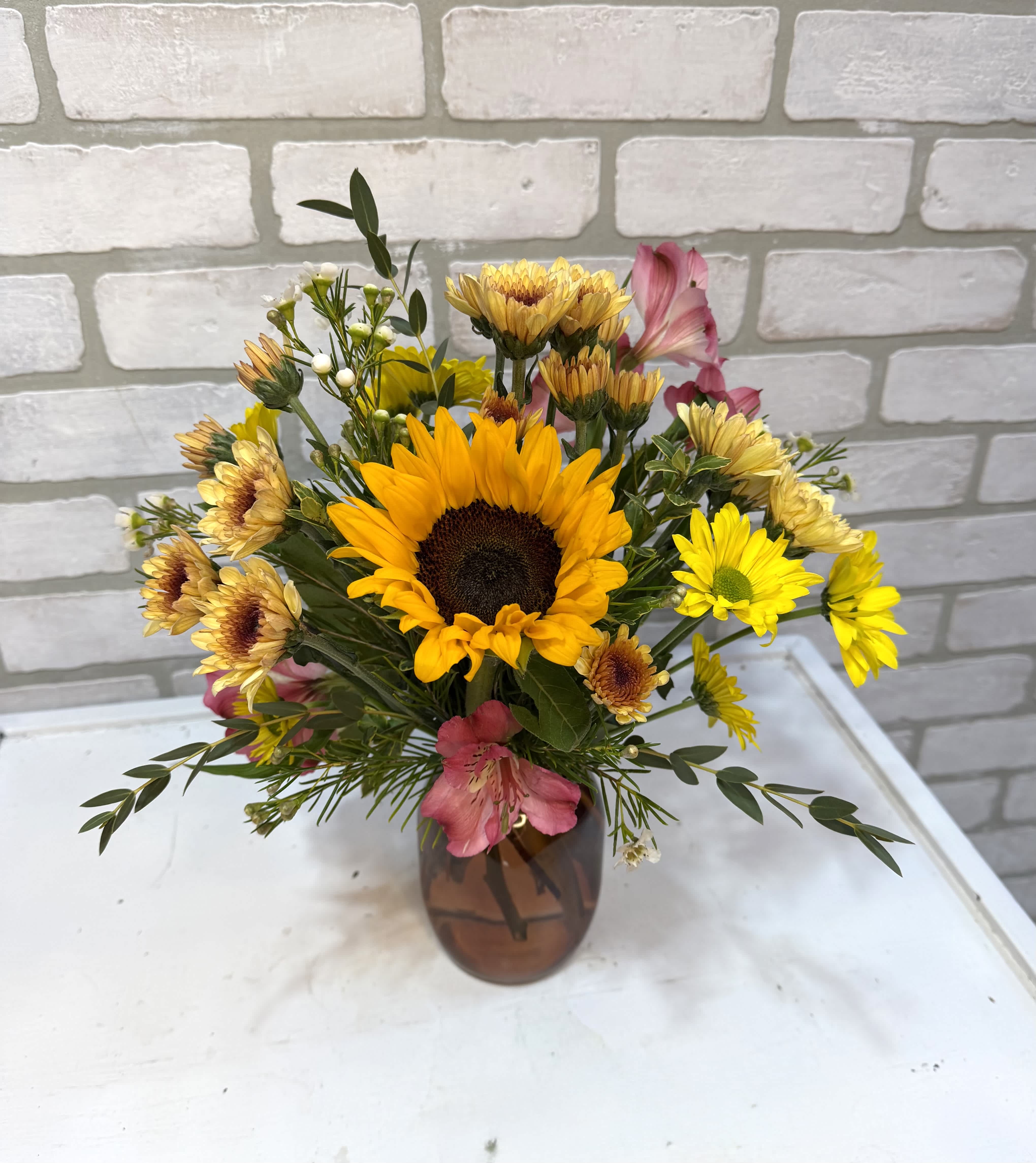Sunflower and daisy bouquet in a brown glass vase