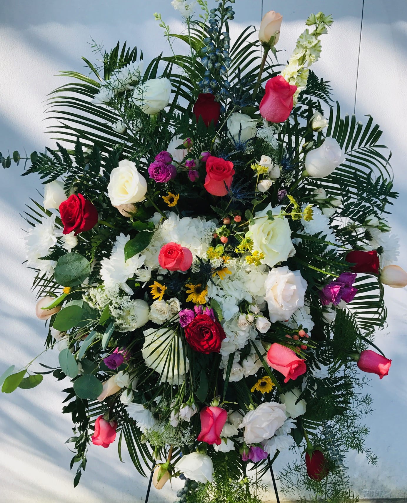 Large standing floral spray with roses, white blooms, and greenery