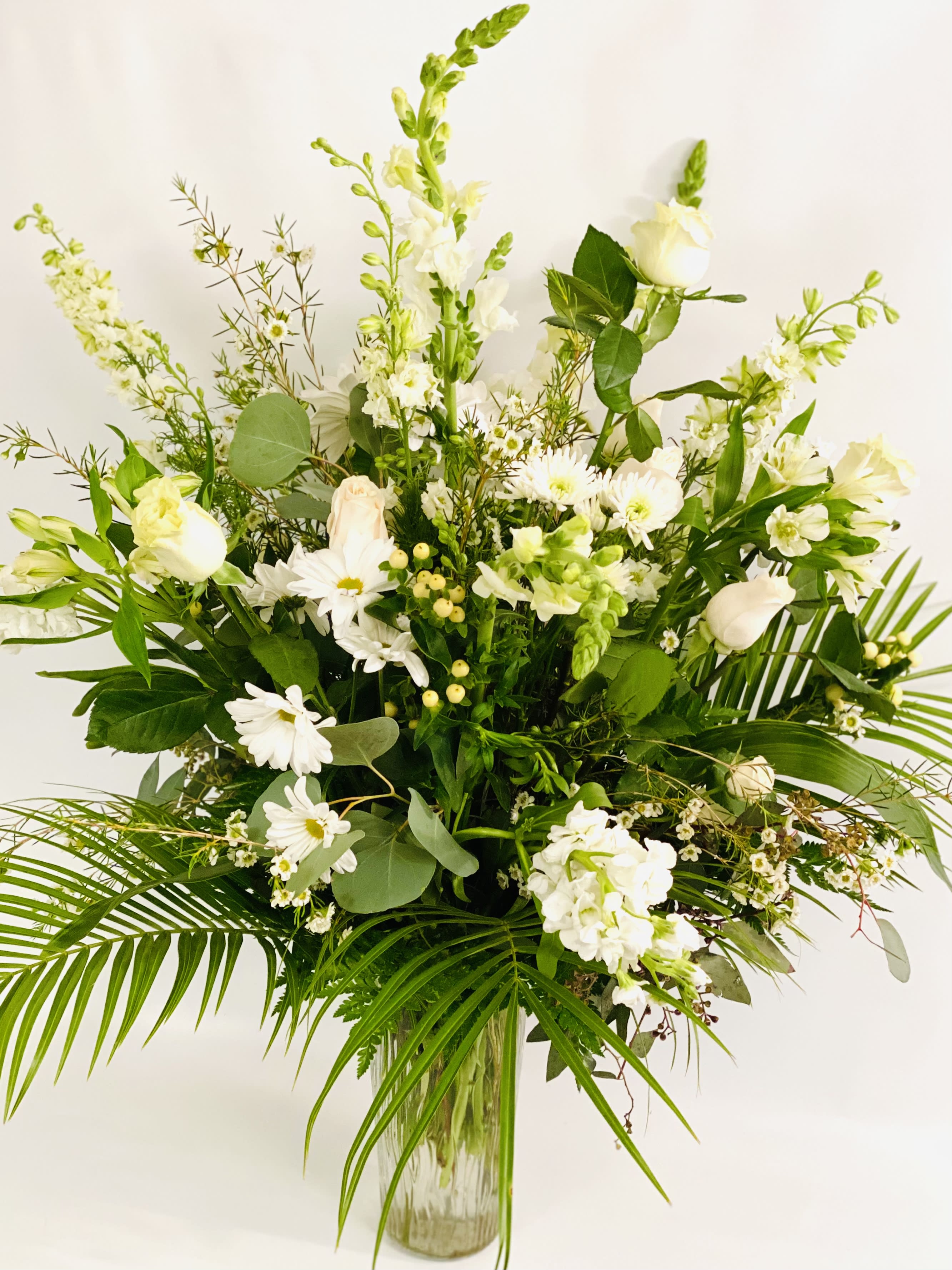Tall white floral arrangement in a clear glass vase