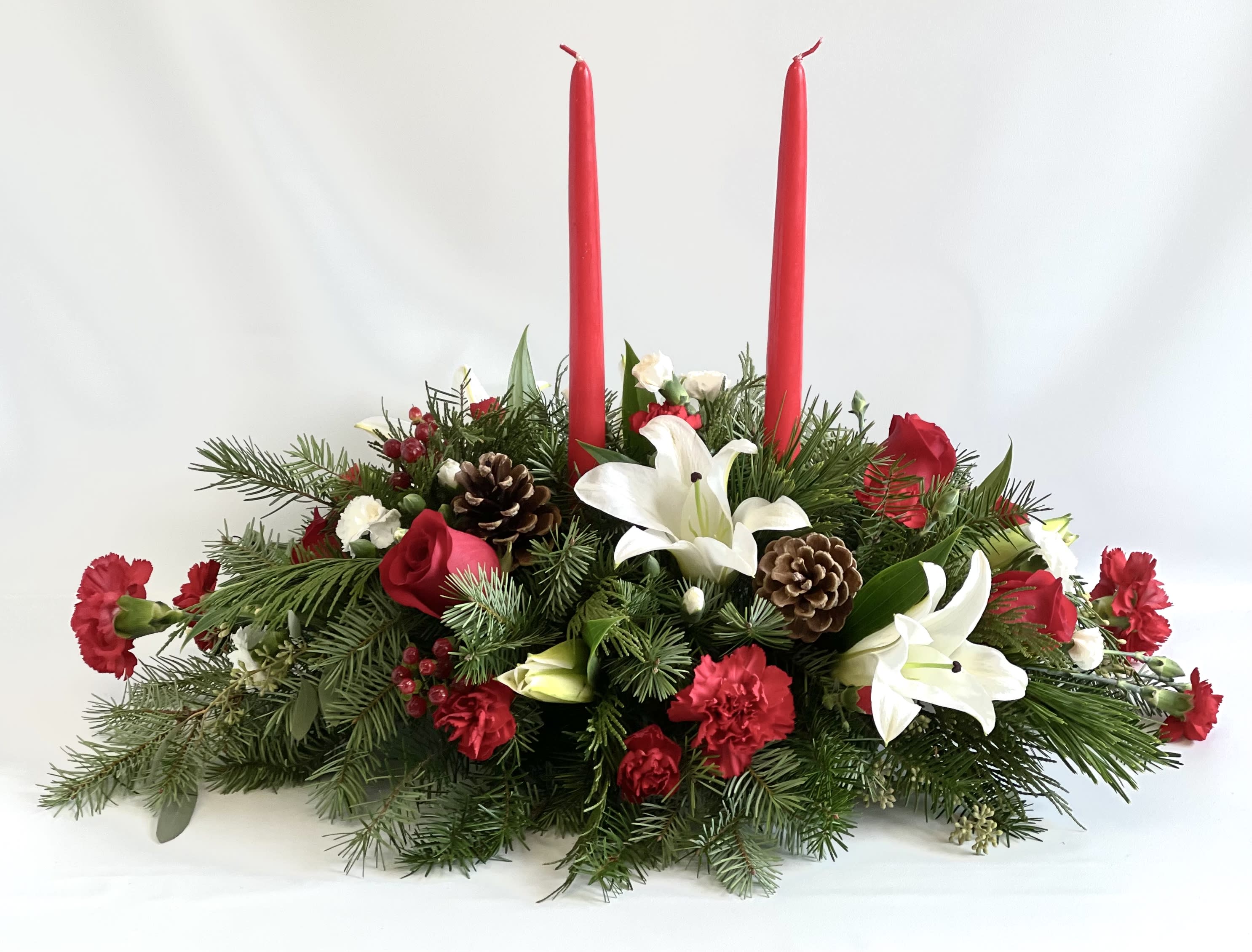 Holiday centerpiece with red candles, white lilies, and pinecones