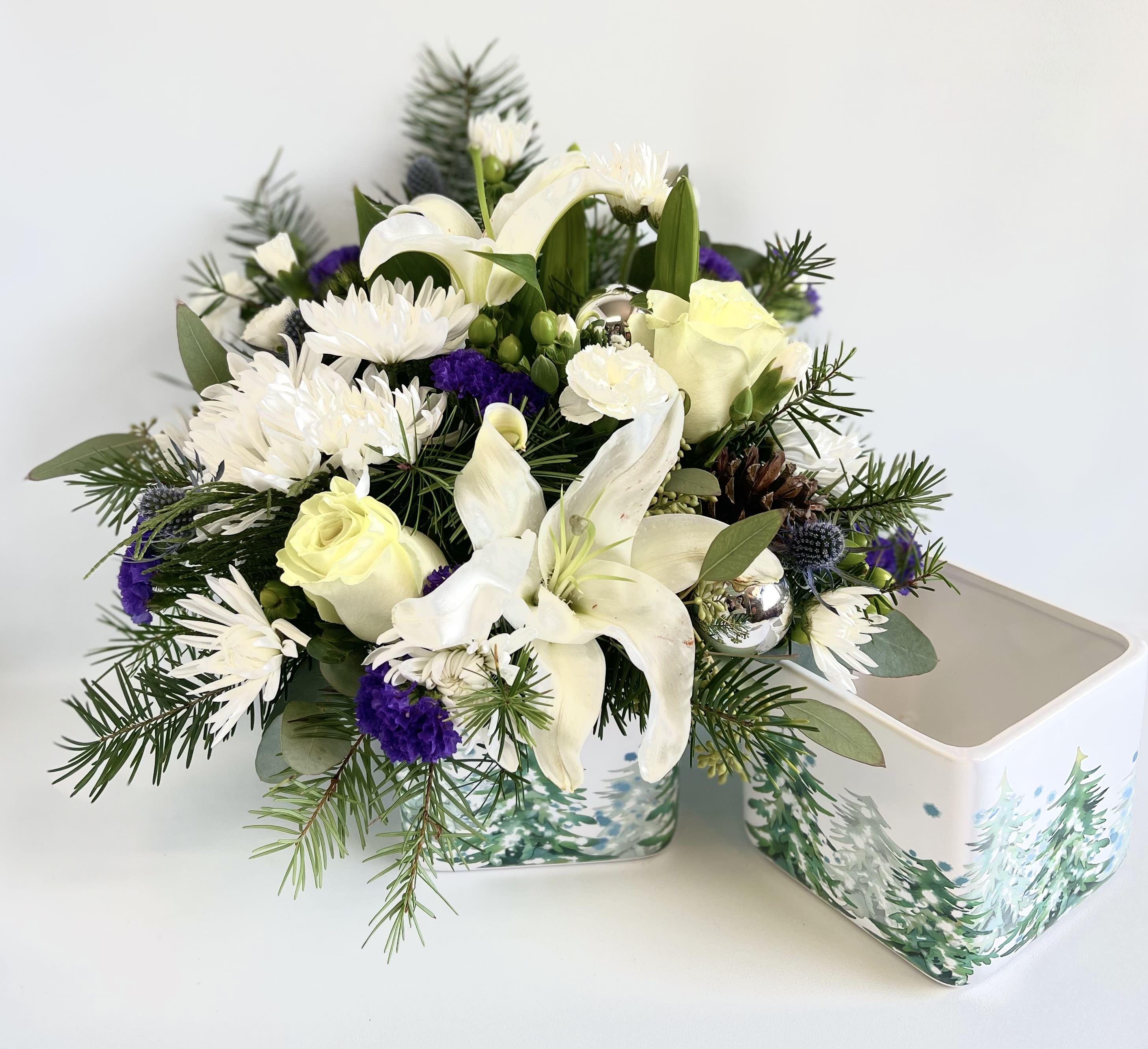 White lilies and roses in a decorative tin container