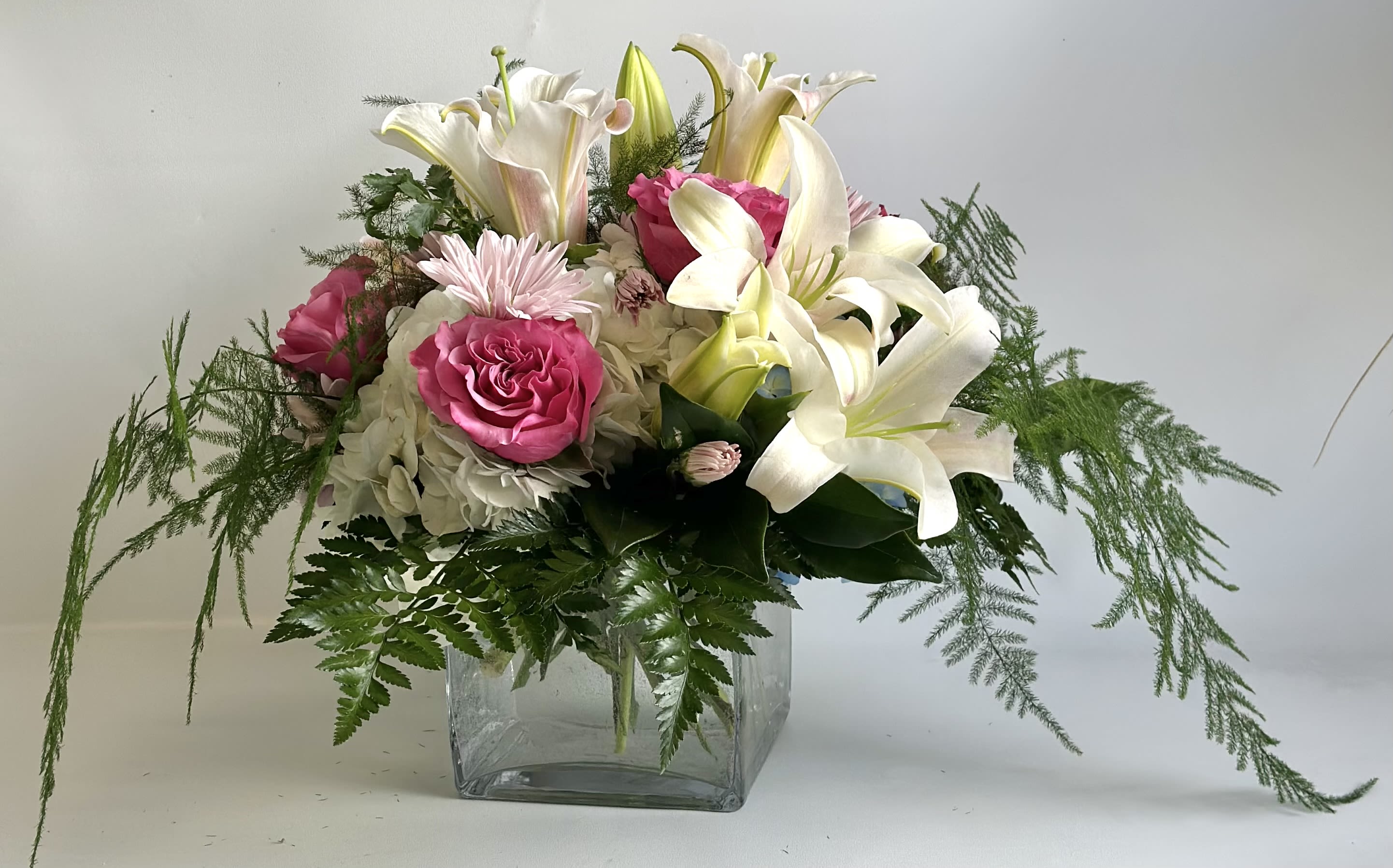 Pink roses and white lilies in a clear glass vase