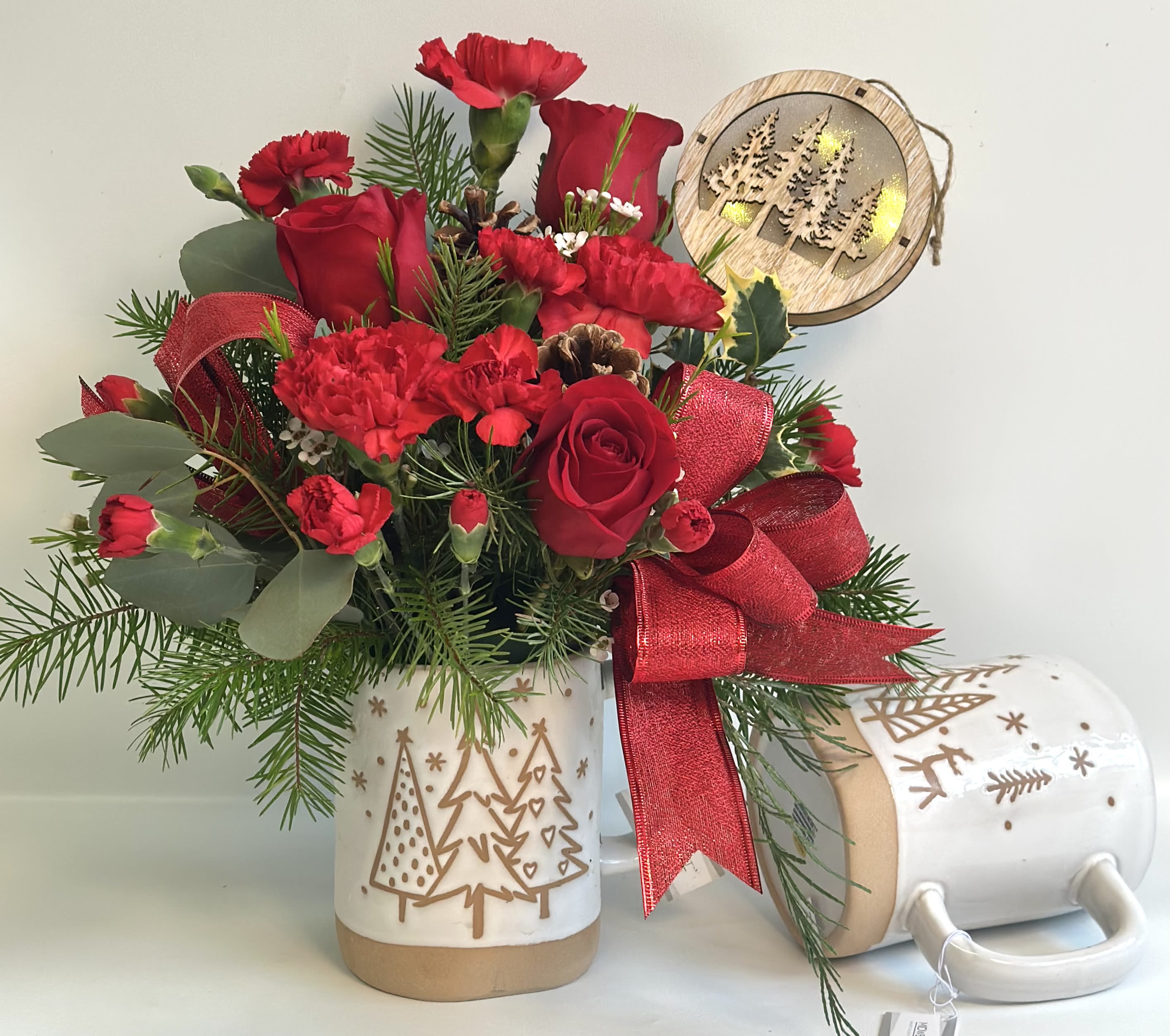 Red roses and carnations in a holiday mug with a red ribbon